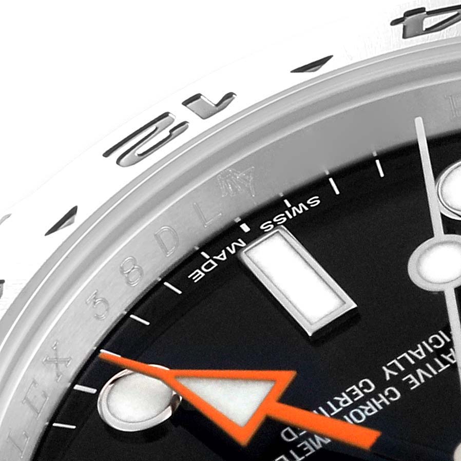 The image shows a close-up of the Rolex Explorer 216570 Men's Stainless Steel Black Dial 216570 Men's Stainless Steel Black Dial watch, highlighting parts of the bezel, dial, and orange hand.