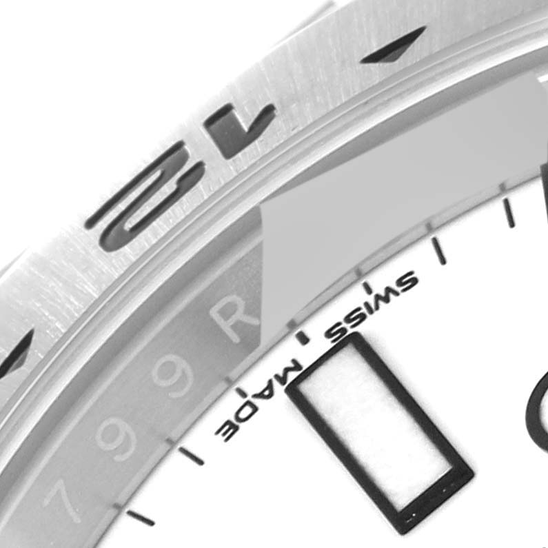 This close-up image of the Rolex Explorer 216570 Men
s Stainless Steel White Dial 216570 Men
s Stainless Steel White Dial watch shows part of the bezel, dial, and minute markings at an angled view.
