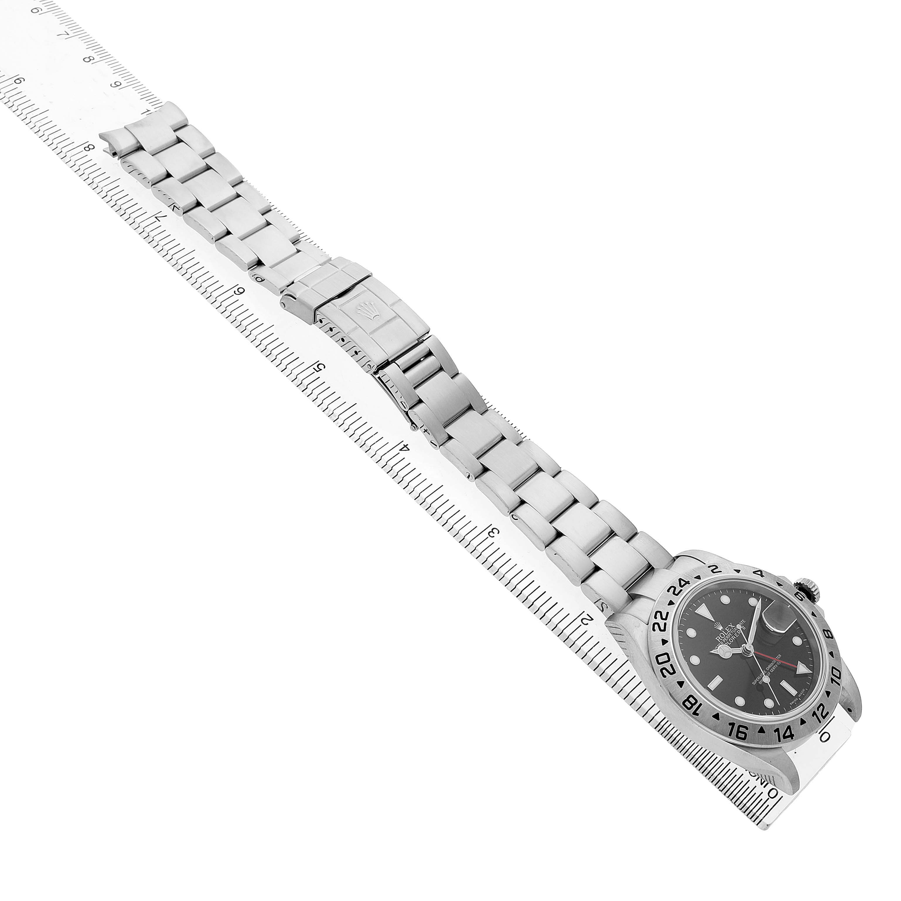 The Rolex Explorer 16570 Men's Stainless Steel Black Dial watch is shown from a top-down angle, highlighting the bracelet and bezel alongside a ruler for measurement.