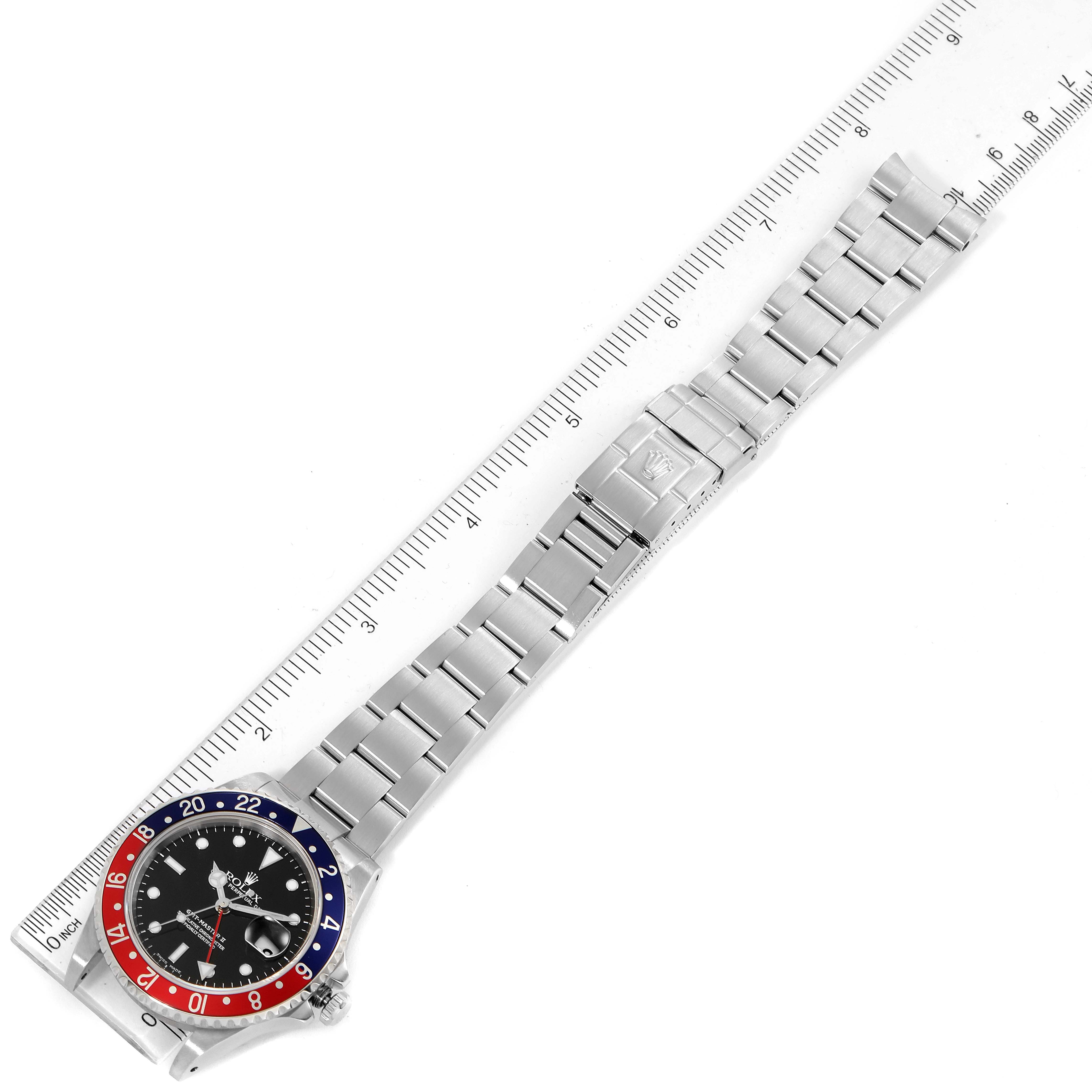 The image shows a top-down view of a Rolex GMT-Master 16710 Men's Stainless Steel Black Dial 16710 Men's Stainless Steel Black Dial watch, highlighting its bezel, dial, and bracelet laid out next to a ruler.