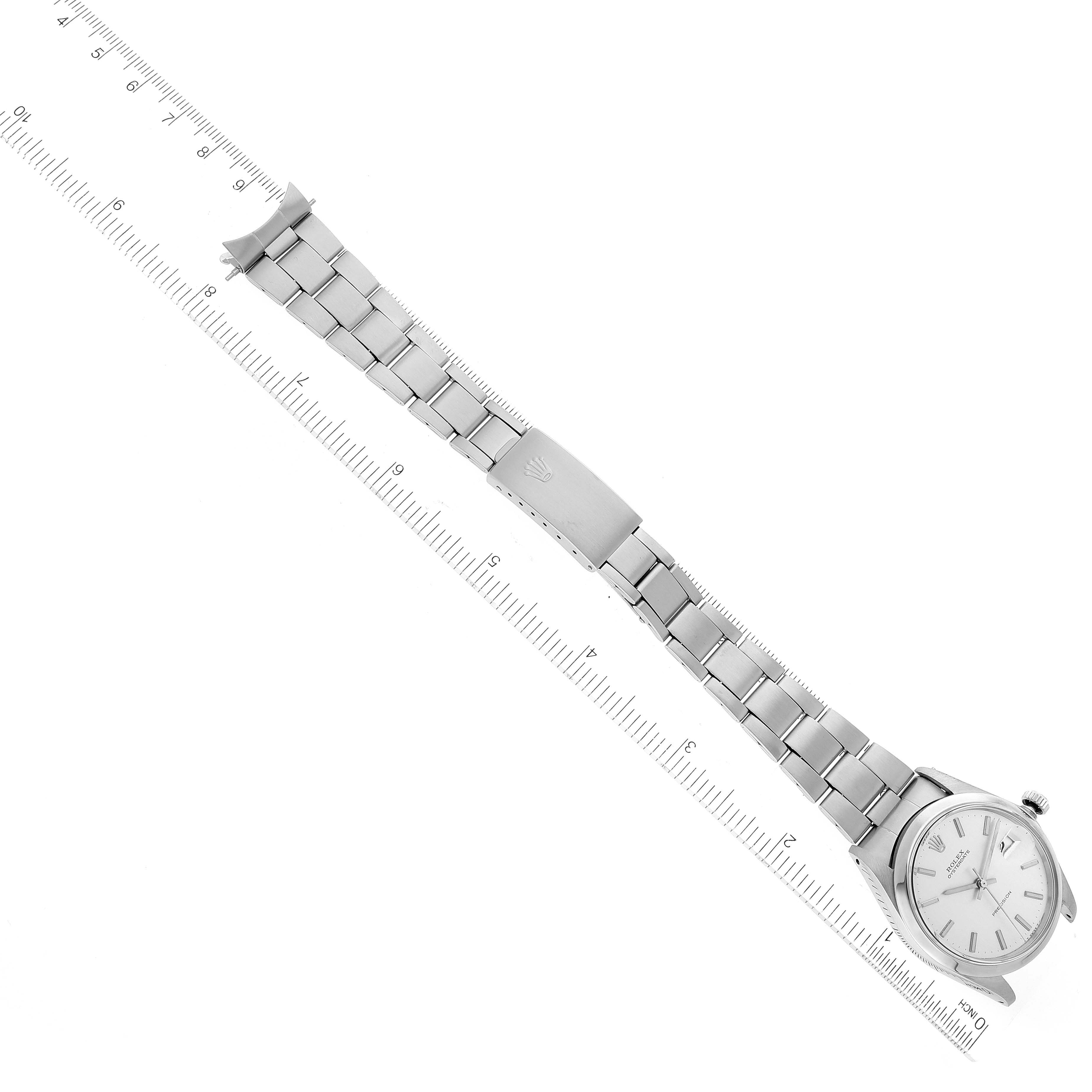 The Rolex Vintage Collection 6694 Men's Stainless Steel Silver Dial 6694 Men's Stainless Steel Silver Dial watch is shown from an overhead angle, displaying the face, bracelet, and clasp next to a ruler.