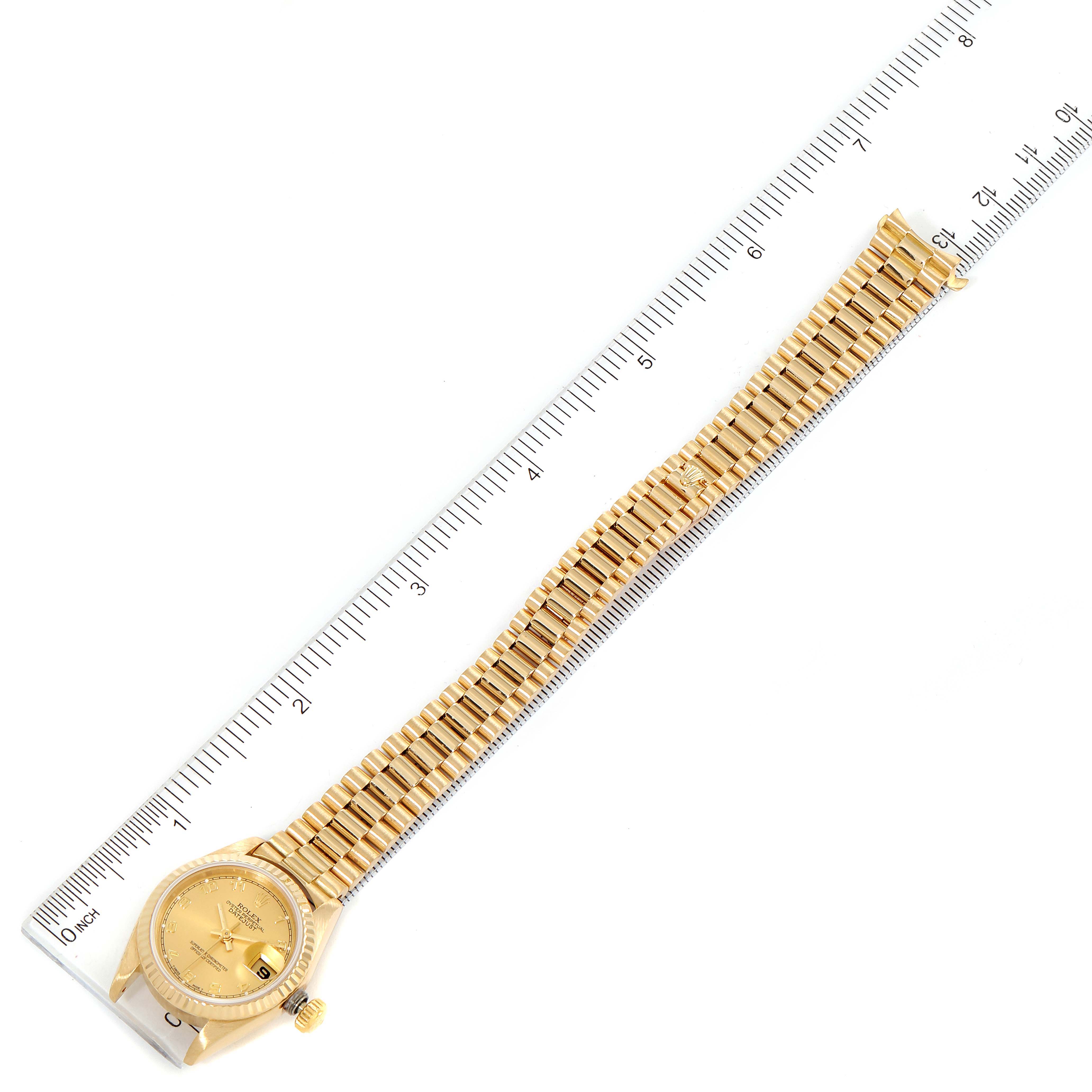 This image shows the full Rolex President 69178 Women
s Yellow Gold Champagne Dial 69178 Women
s Yellow Gold Champagne Dial model watch laid flat alongside a ruler.