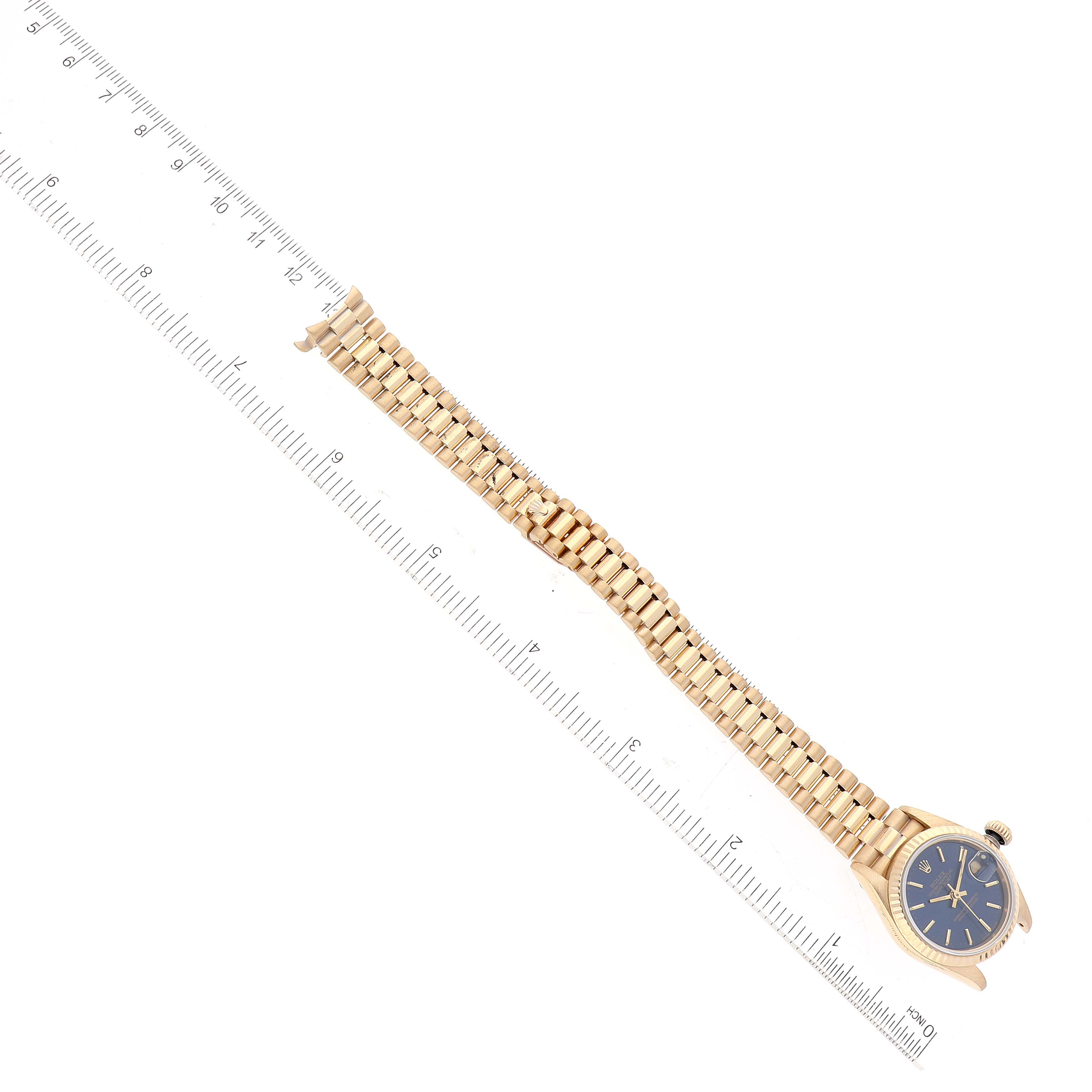 The image shows a Rolex President 69178 Women's Yellow Gold Blue Dial 69178 Women's Yellow Gold Blue Dial model watch laid flat, with its band extended and aligned next to a ruler for scale.