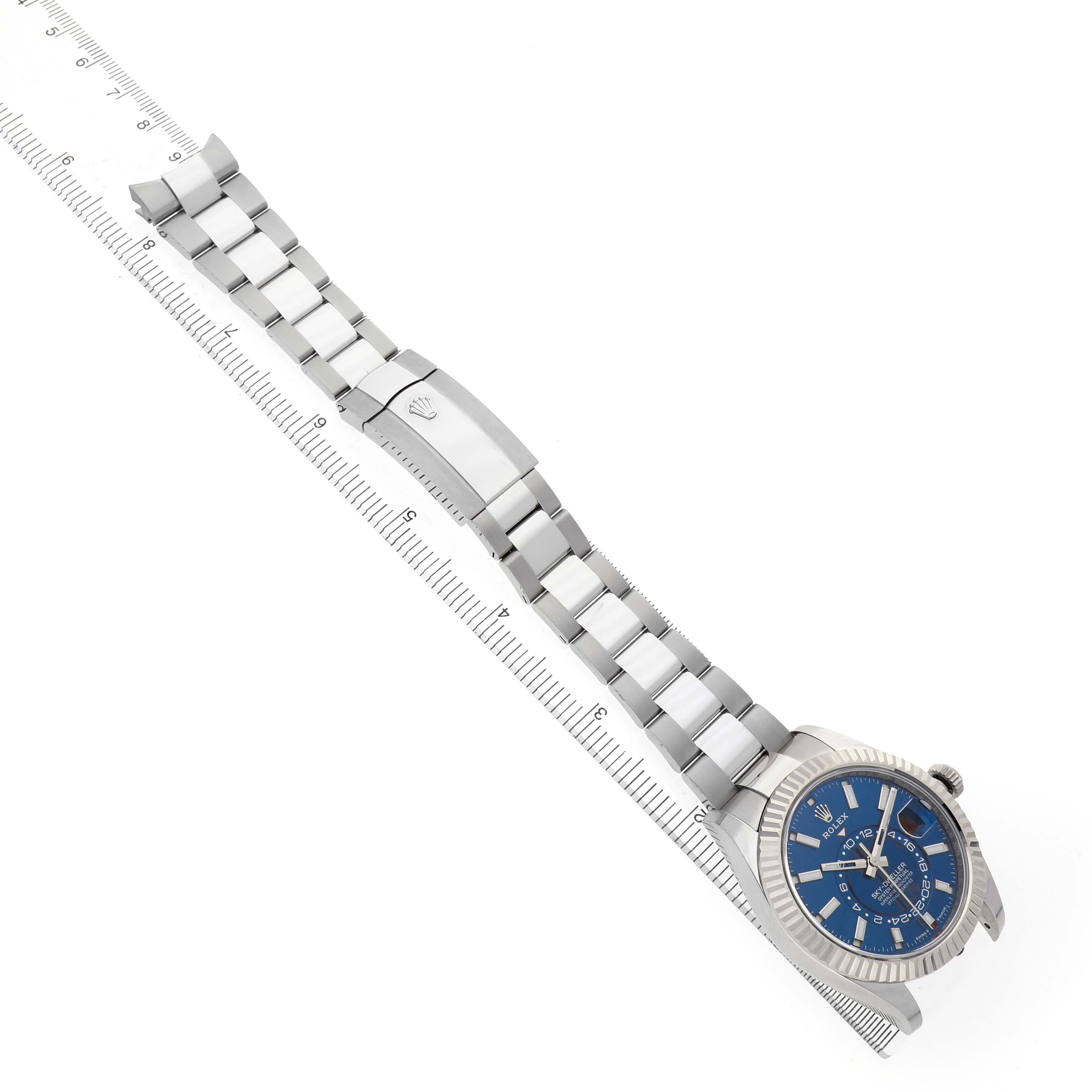 The image shows a Rolex Sky-Dweller 336934 Men's Stainless Steel Blue Dial watch from a top angle, highlighting the face, bracelet, and clasp, alongside a ruler for scale.