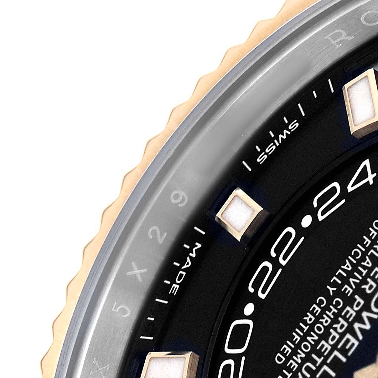 The image shows a close-up of the Rolex Sky-Dweller 326933 Men's Steel and Gold (two tone) Black Dial's bezel, part of the dial, and hour markers from an angle focusing on the side.