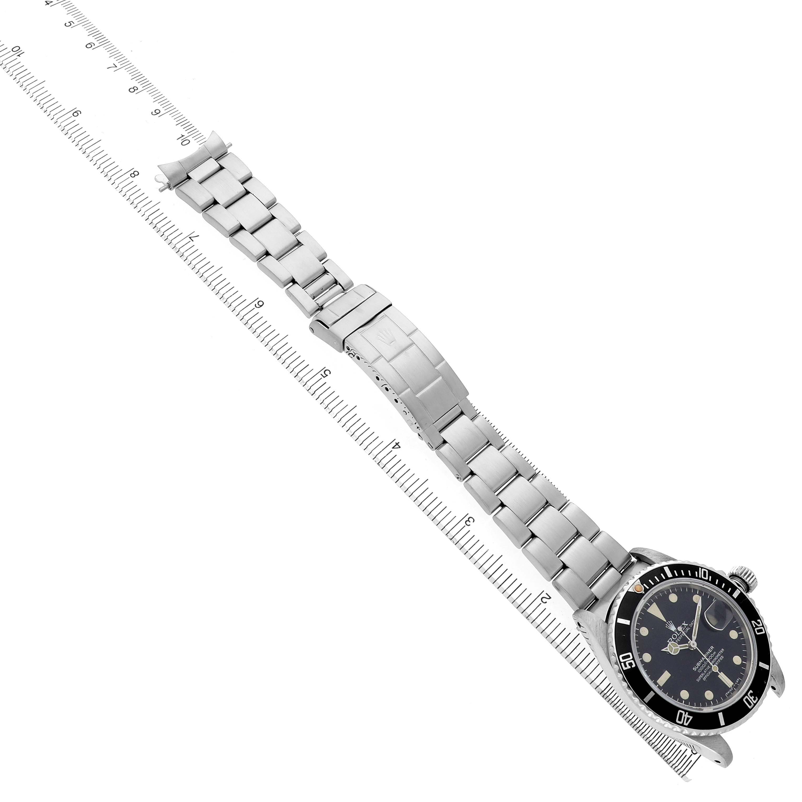 The Rolex Submariner 16800 Men's Stainless Steel Black Dial watch is shown from a top view, with its bracelet fully extended and aligned with a ruler.