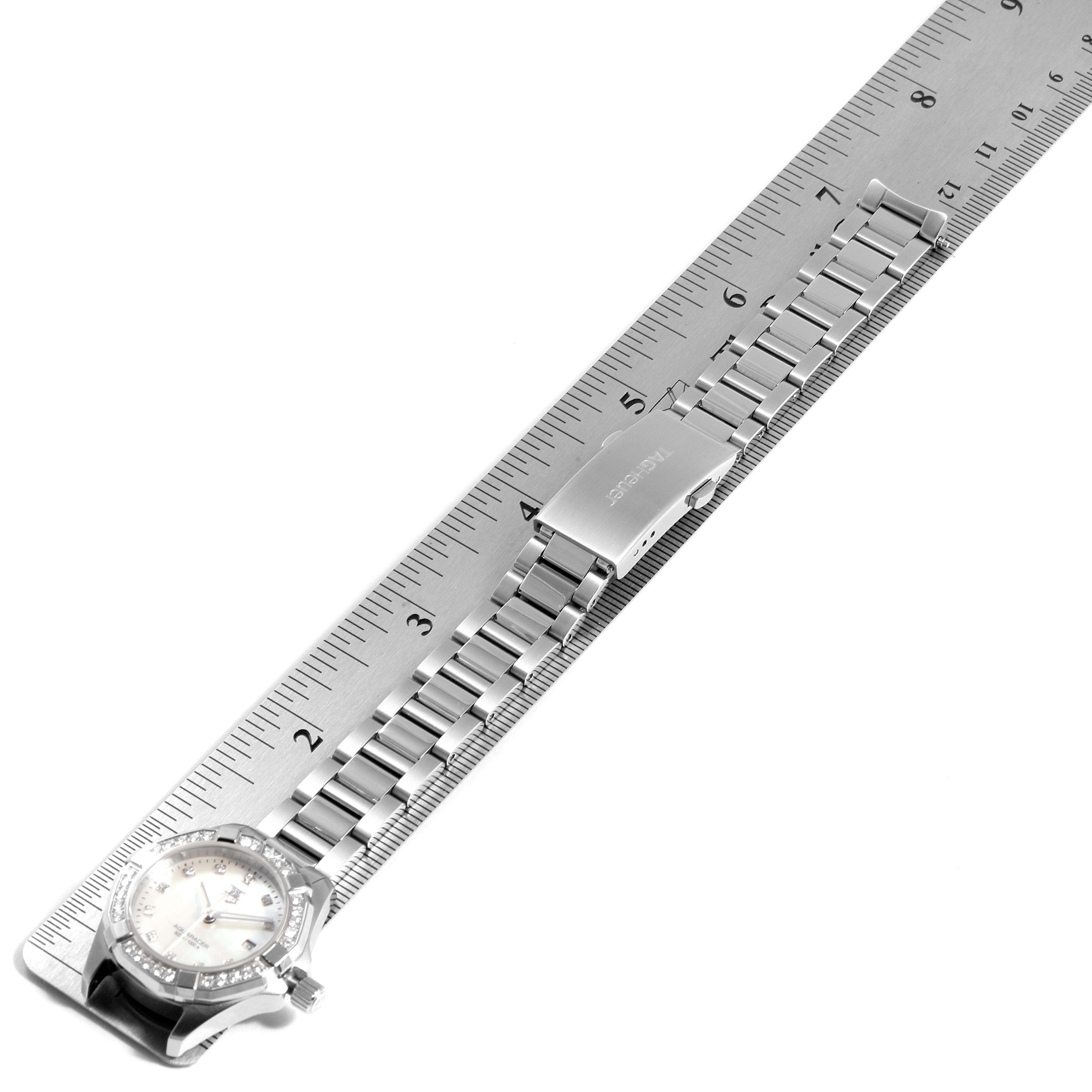 The image shows a Tag Heuer Aquaracer WAY1414.BA0920 Women's Stainless Steel Mother of Pearl Dial WAY1414.BA0920 Women's Stainless Steel Mother of Pearl Dial watch placed alongside a ruler, displaying the watch face and metal bracelet.