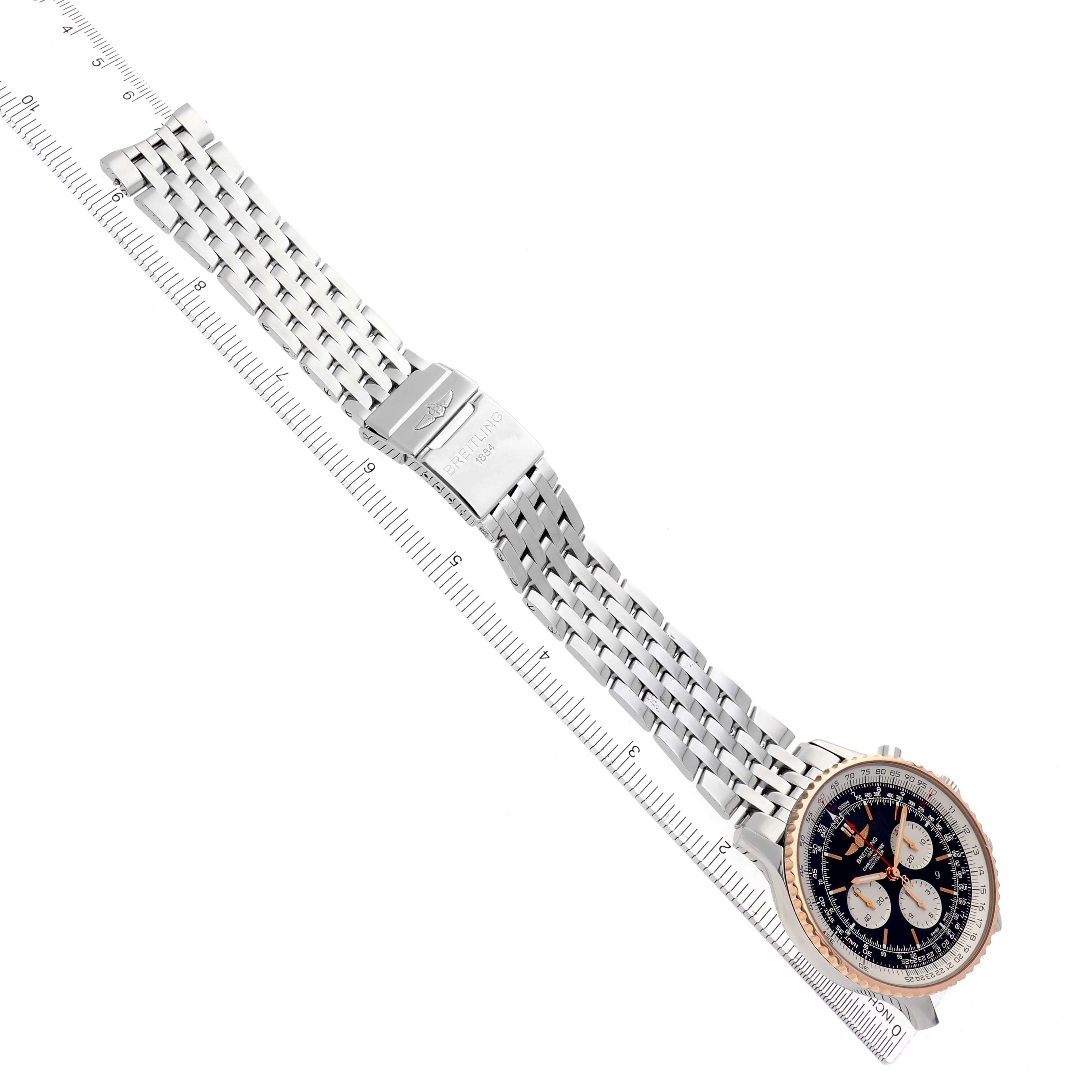 The Breitling Navitimer UB0127 Men
s Steel and Gold (two tone) Black Dial UB0127 Men
s Steel and Gold (two tone) Black Dial watch is shown from a top-down angle highlighting the face and bracelet, next to a ruler.