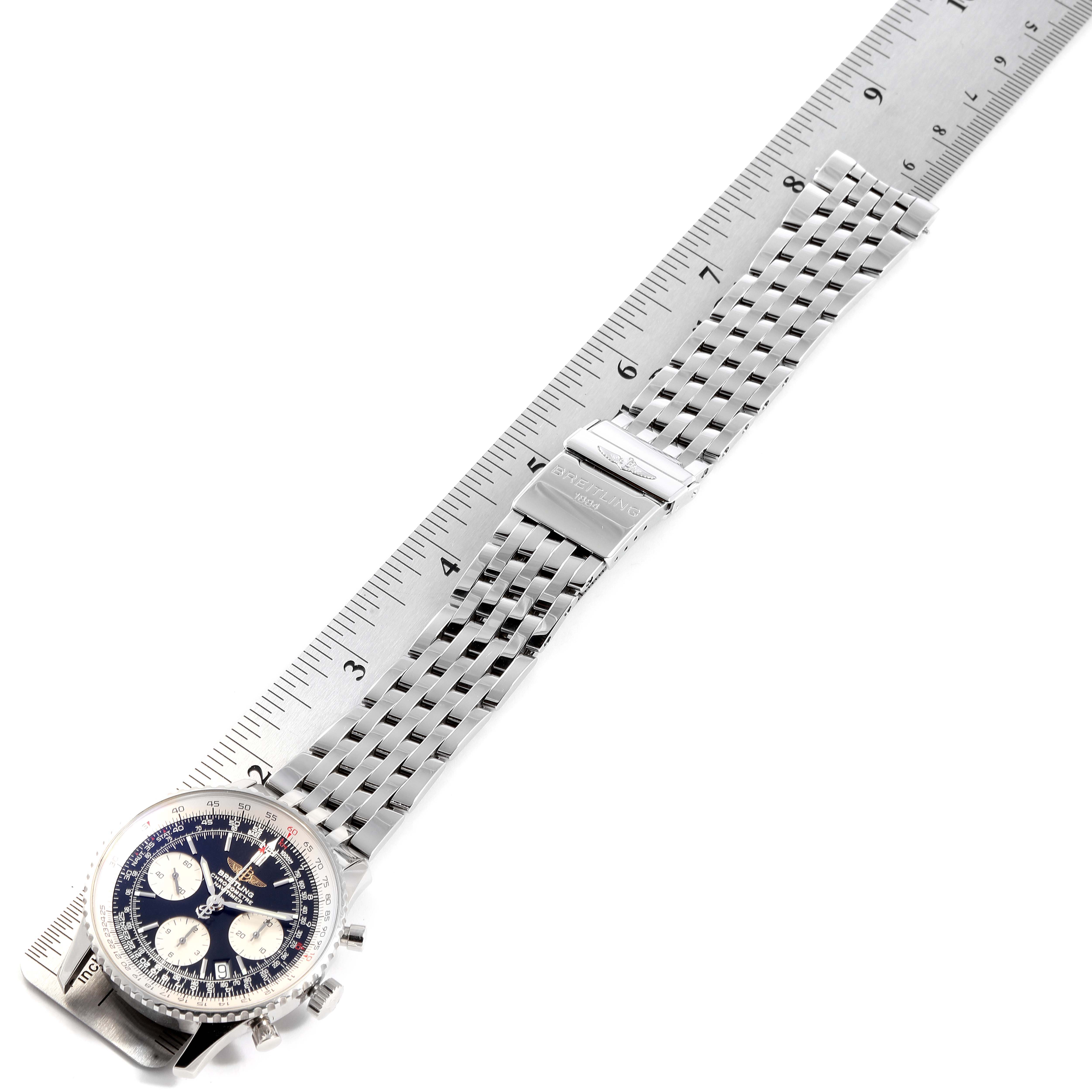 This image shows an overhead view of the Breitling Navitimer A23322 Men
s Stainless Steel Black Dial A23322 Men
s Stainless Steel Black Dial watch, displaying the dial, the full length of the metal bracelet, and the clasp alongside a ruler for size reference.