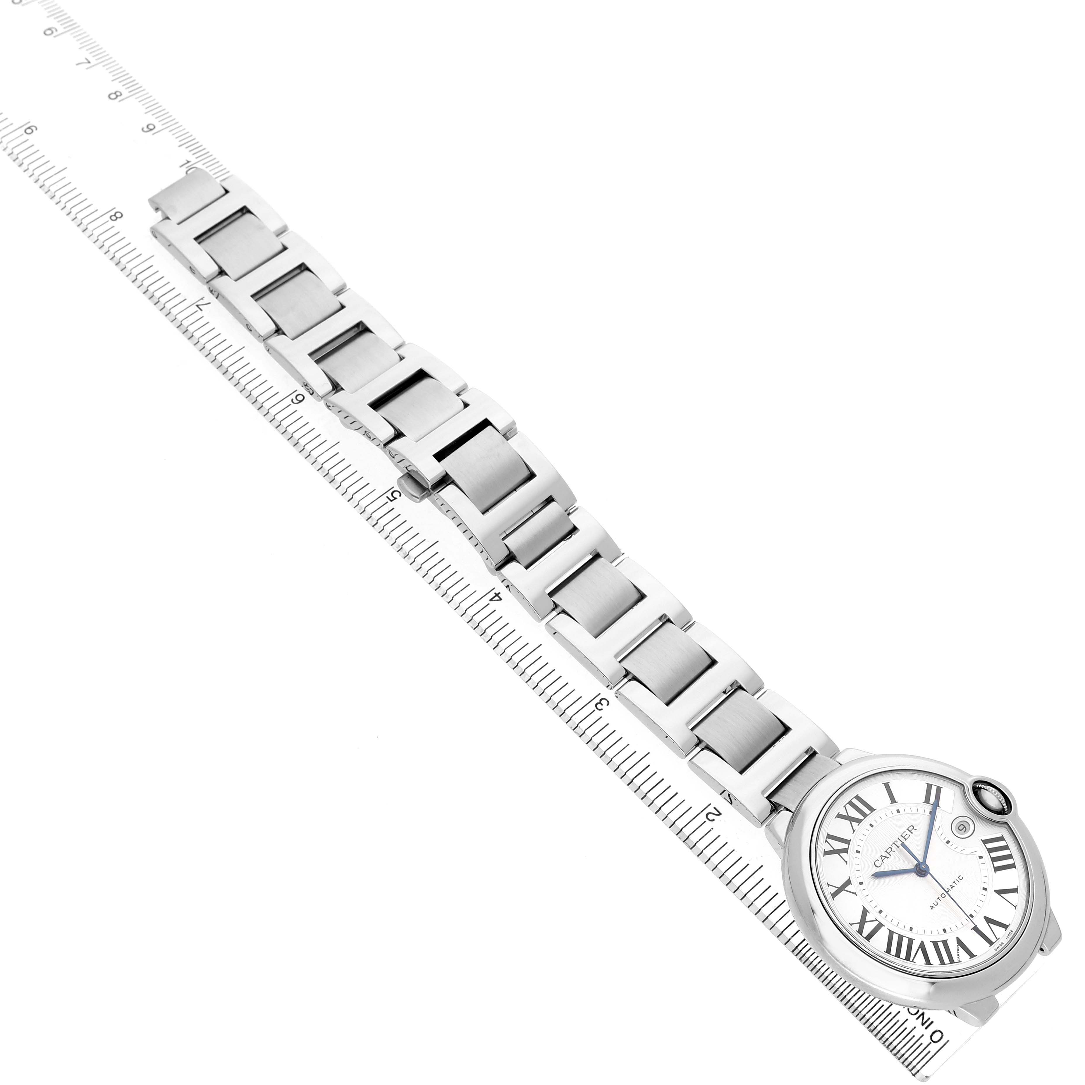 The image shows a top view of the Cartier Ballon Bleu W69012Z4 Men's Stainless Steel Silver Dial watch, featuring its bracelet and face alongside a ruler.