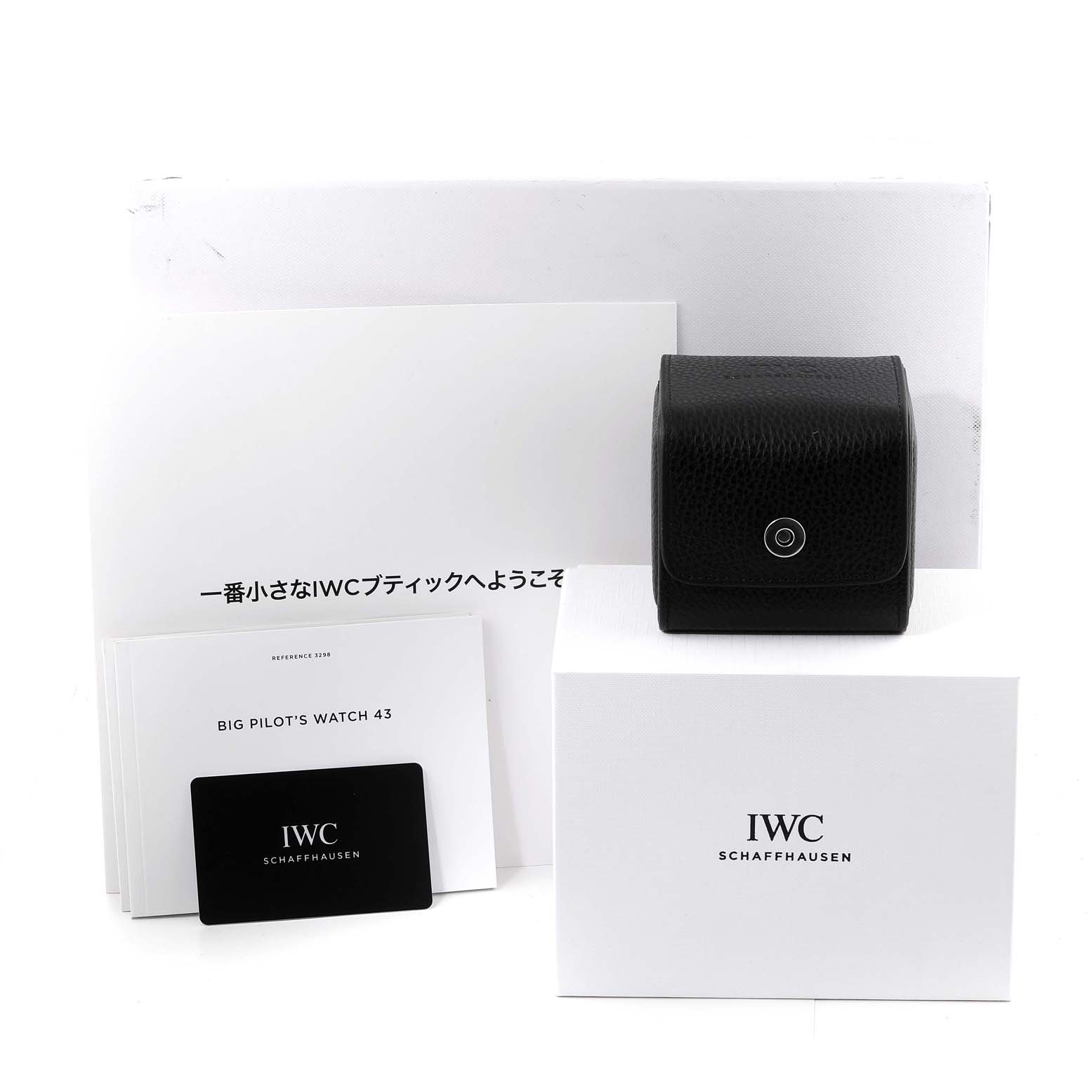 The image shows packaging and accessories for an IWC Big Pilot's Watch 43, including boxes, a black case, and documentation.