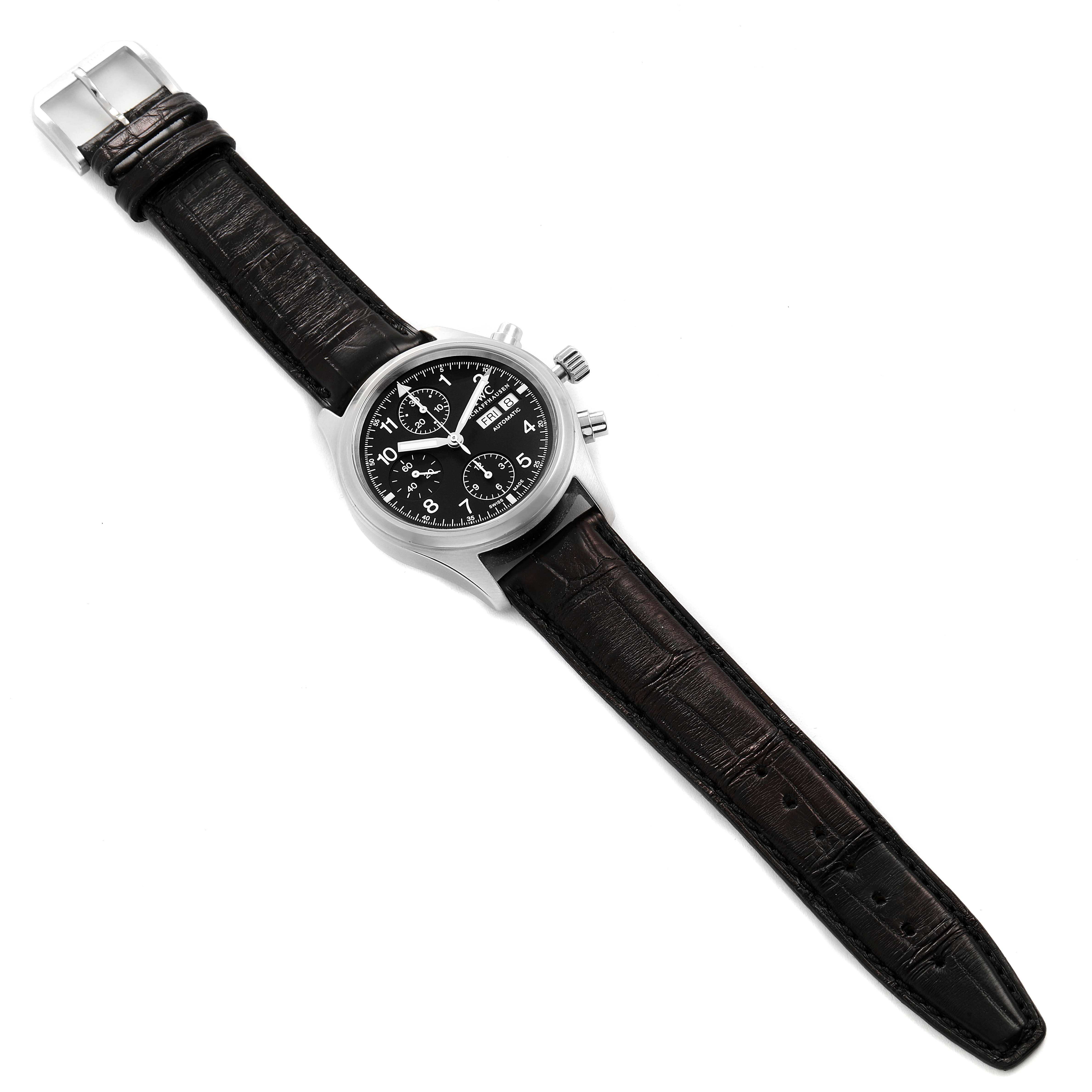 The image shows an overhead view of an IWC Pilot IW370603 Men's Stainless Steel Black Dial IW370603 Men's Stainless Steel Black Dial model watch, displaying its face, strap, clasp, and chronograph pushers.