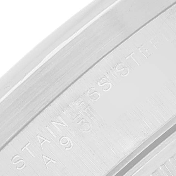 The image is a close-up of the side engraving on a Rolex Date 15210 Men's Stainless Steel Blue Dial 15210 Men's Stainless Steel Blue Dial model watch, showing the markings on its stainless steel case.