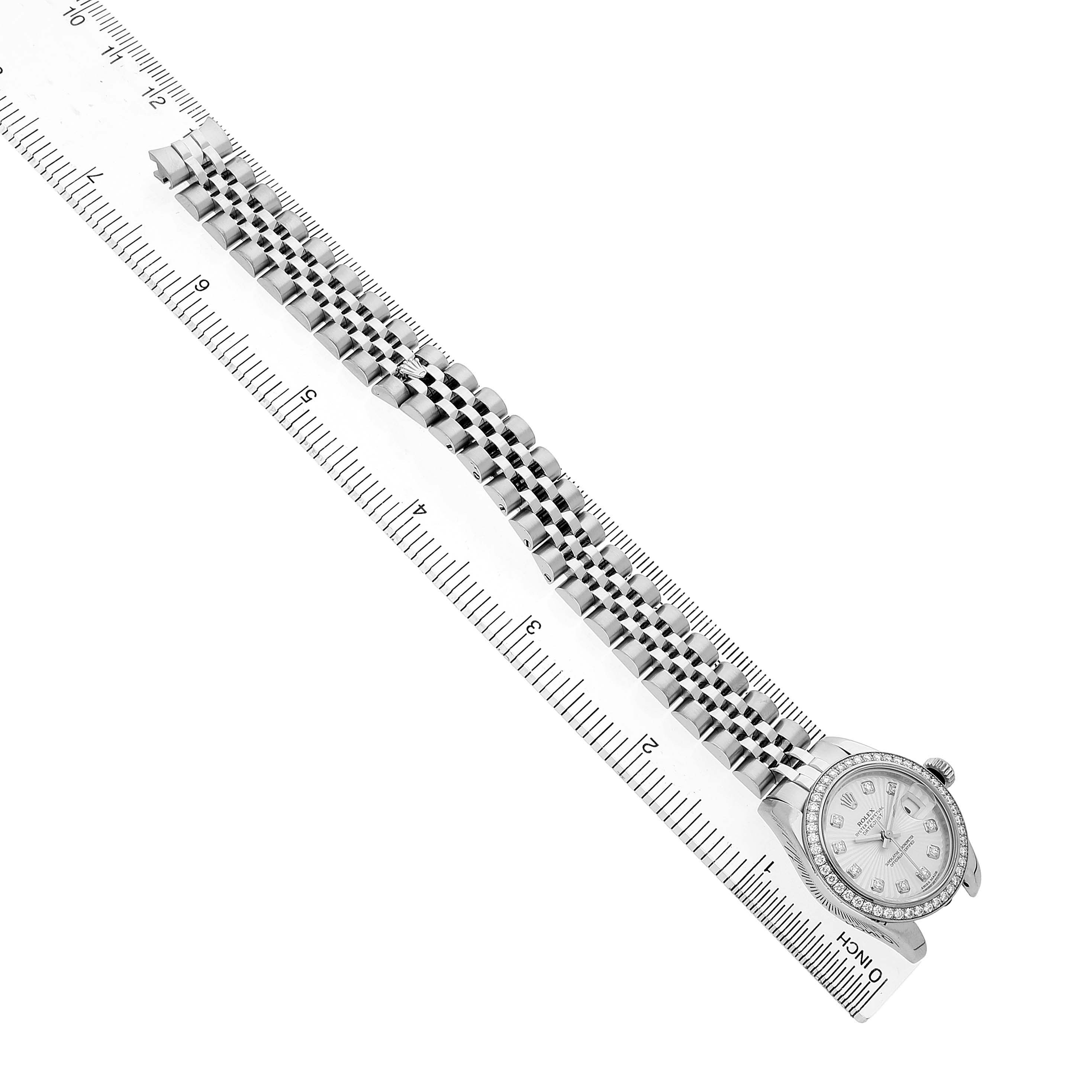 The Rolex Datejust 179384 Women's Stainless Steel Silver Dial watch is shown from a top-down angle with its bracelet extended alongside a ruler.