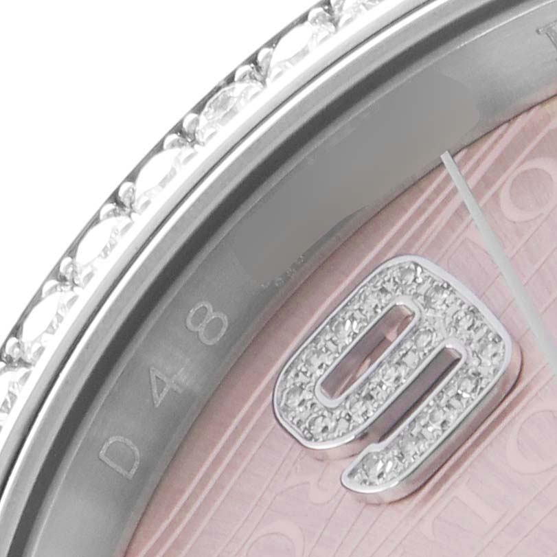 The image shows a close-up of the Rolex Datejust 116189 Men
s White Gold Pink Dial 116189 Men
s White Gold Pink Dial watch, highlighting the diamond-set bezel and a portion of the dial with a numeral.
