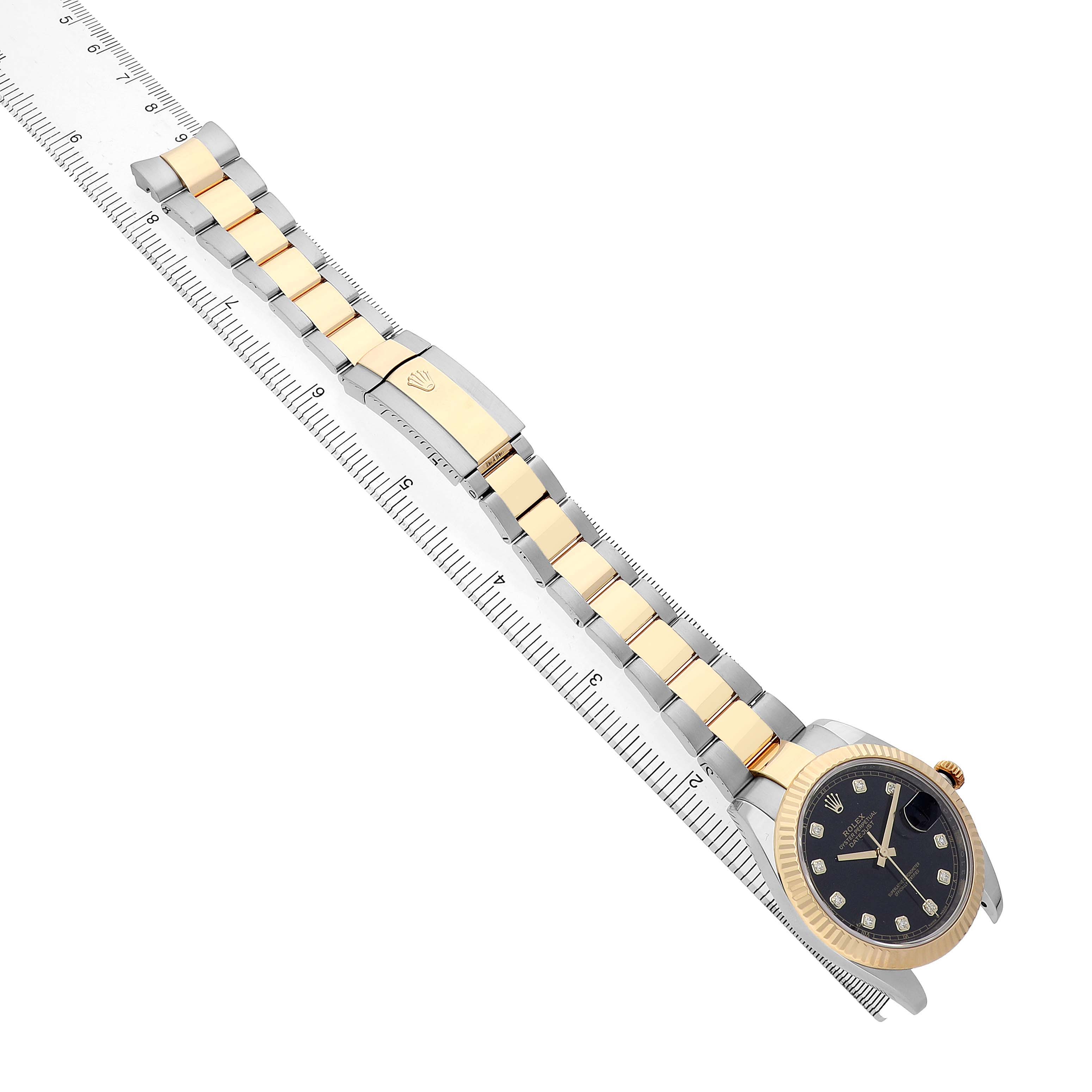 The Rolex Datejust 126333 Men's Steel and Gold (two tone) Black Dial watch is shown at an angle displaying the face, bezel, bracelet, and clasp next to a ruler.