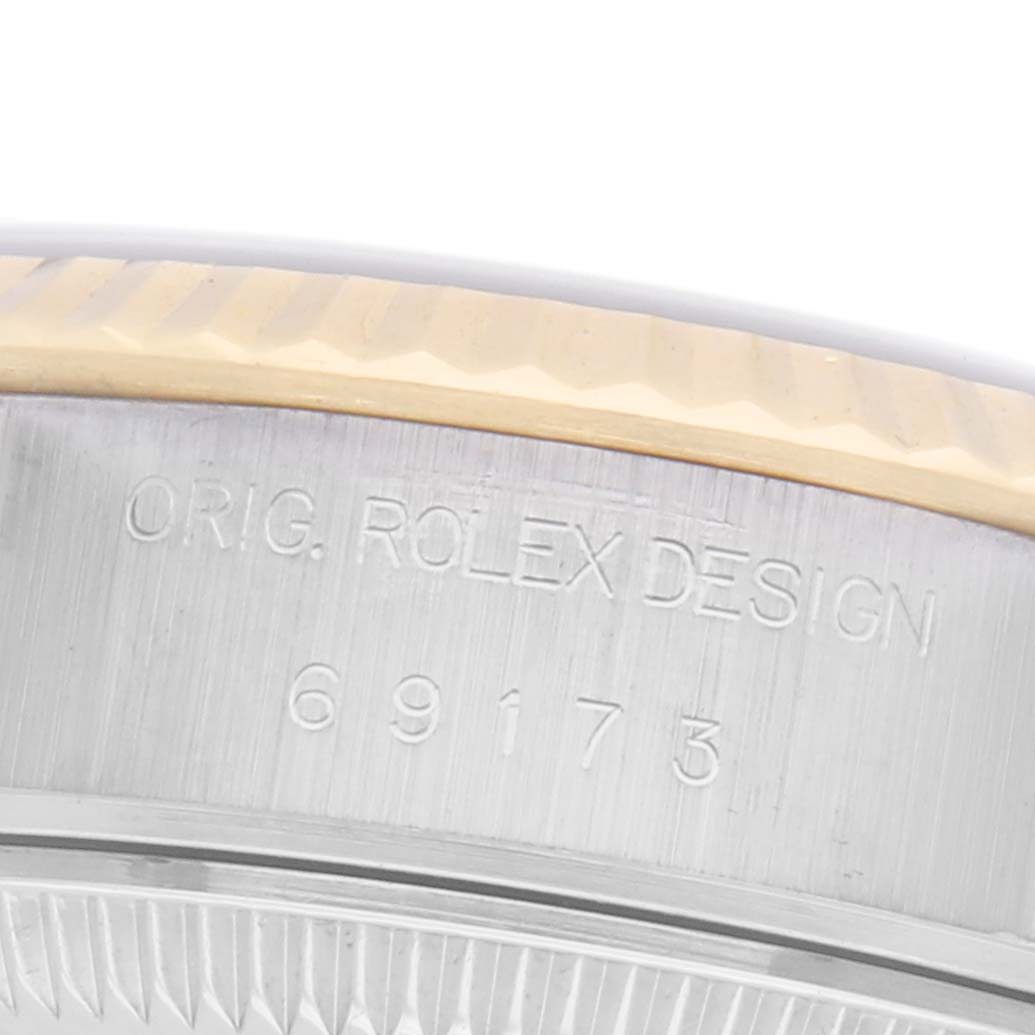 The image shows a close-up of the Rolex Datejust 69173 Women
s Steel and Gold (two tone) Blue Dial 69173 Women
s Steel and Gold (two tone) Blue Dial model
s case side, displaying engraving details and the fluted bezel.