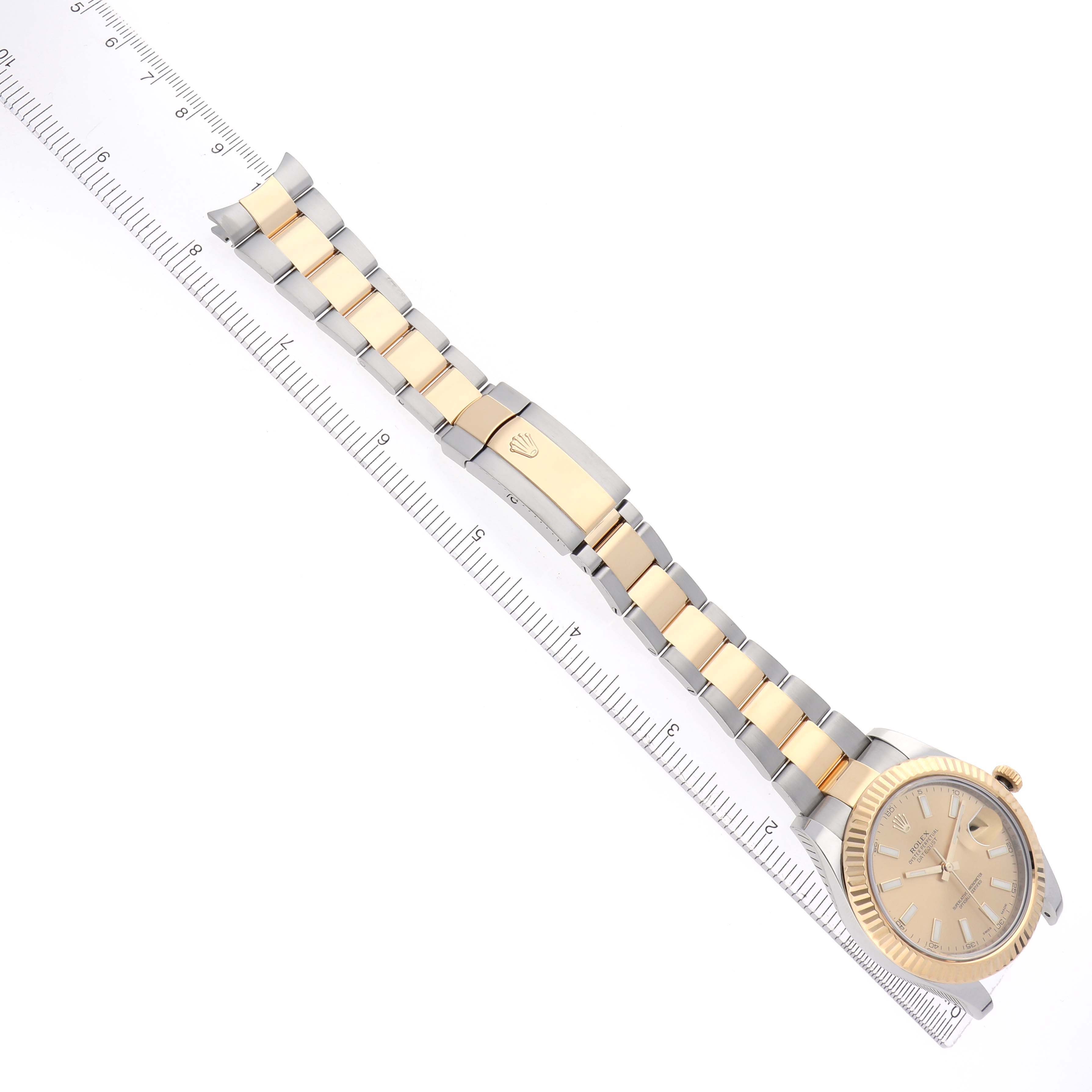 The Rolex Datejust 116333 Men
s Steel and Gold (two tone) Champagne Dial 116333 Men
s Steel and Gold (two tone) Champagne Dial watch is shown from a top angle, displaying the bracelet, clasp, and face against a ruler for scale.