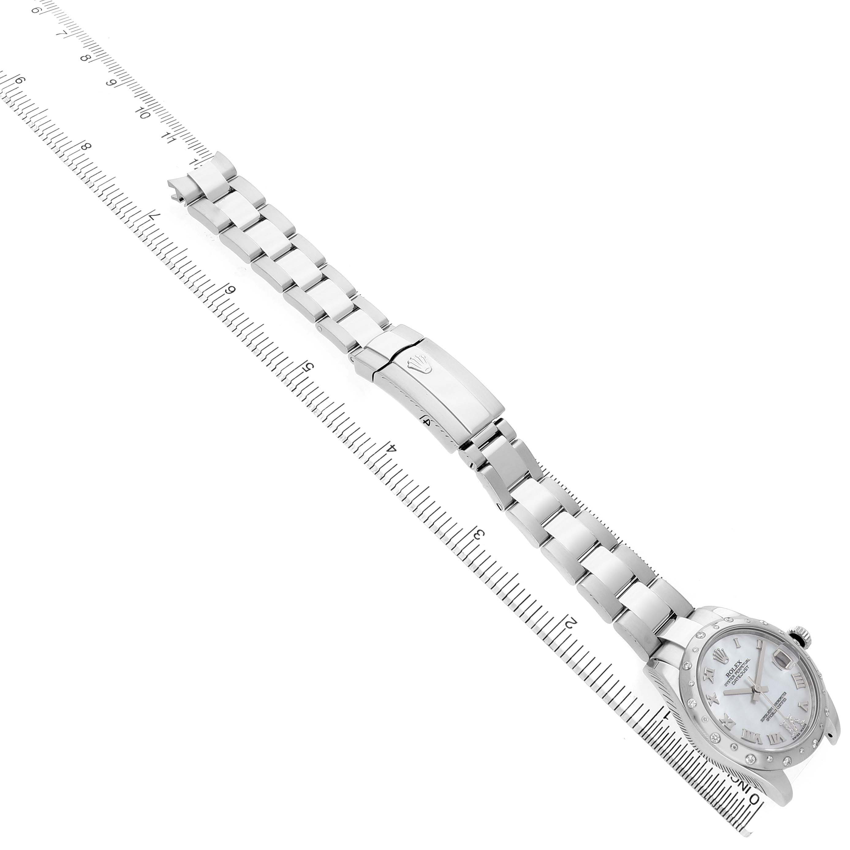 The Rolex Datejust 178344 Women's Stainless Steel Mother of Pearl Dial watch is shown from an overhead angle, displaying the face, bracelet, and clasp, alongside a measuring scale.