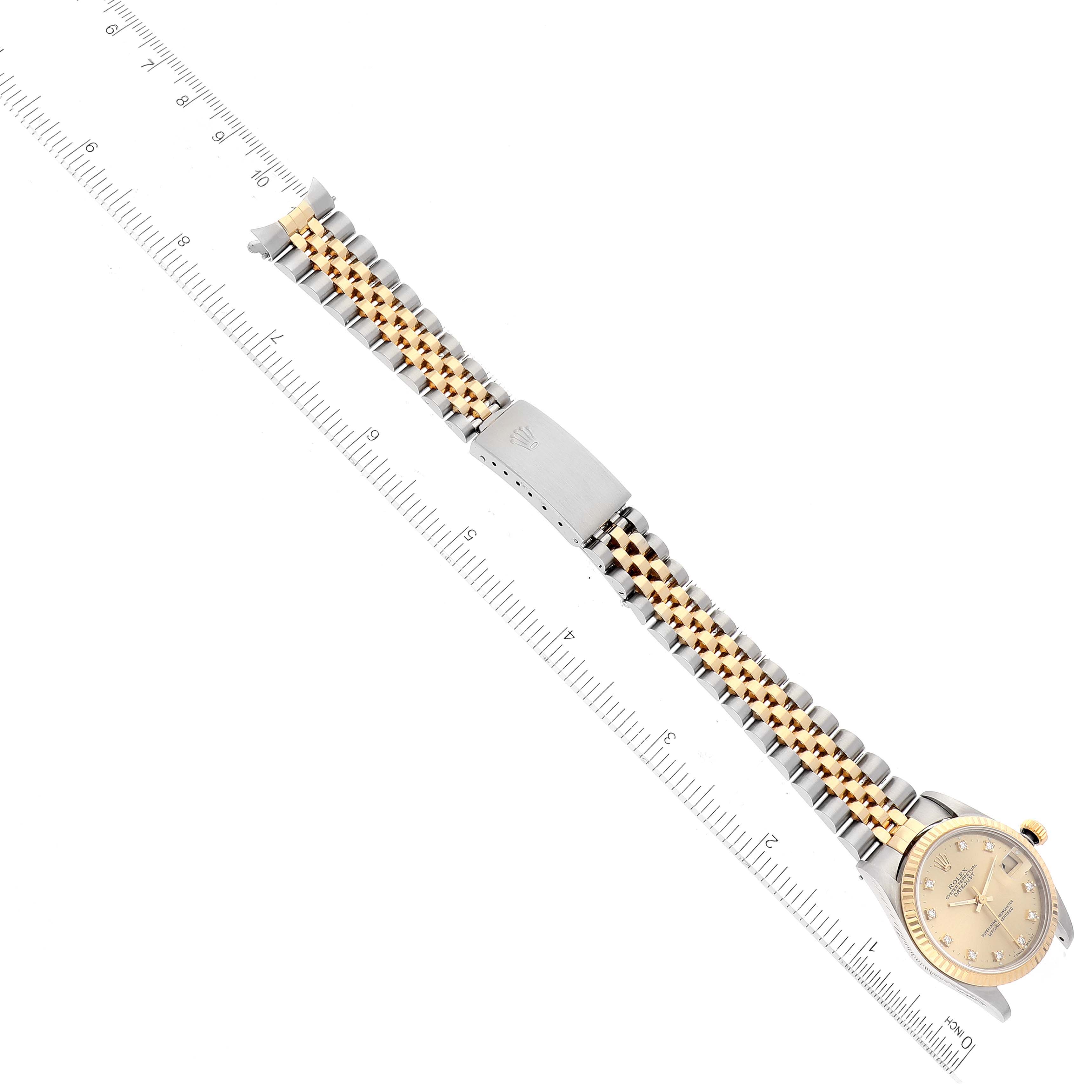 The image shows a Rolex Mid-Size 68273 Women's Steel and Gold (two tone) Champagne Dial 68273 Women's Steel and Gold (two tone) Champagne Dial watch laid flat, highlighting its face, bezel, and two-tone bracelet with a clasp, positioned next to a ruler.