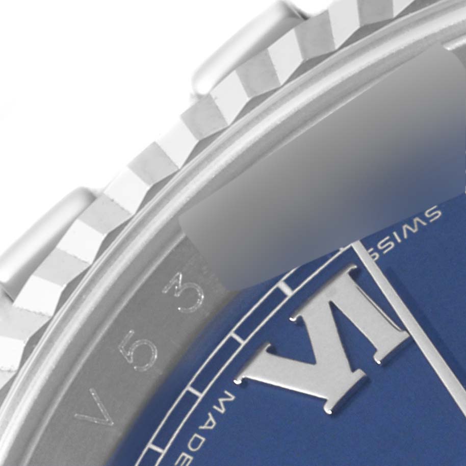 This close-up of a Rolex Datejust 116234 Men's Stainless Steel Blue Dial 116234 Men's Stainless Steel Blue Dial watch showcases the fluted bezel, part of the blue dial, and "VI" hour marker.