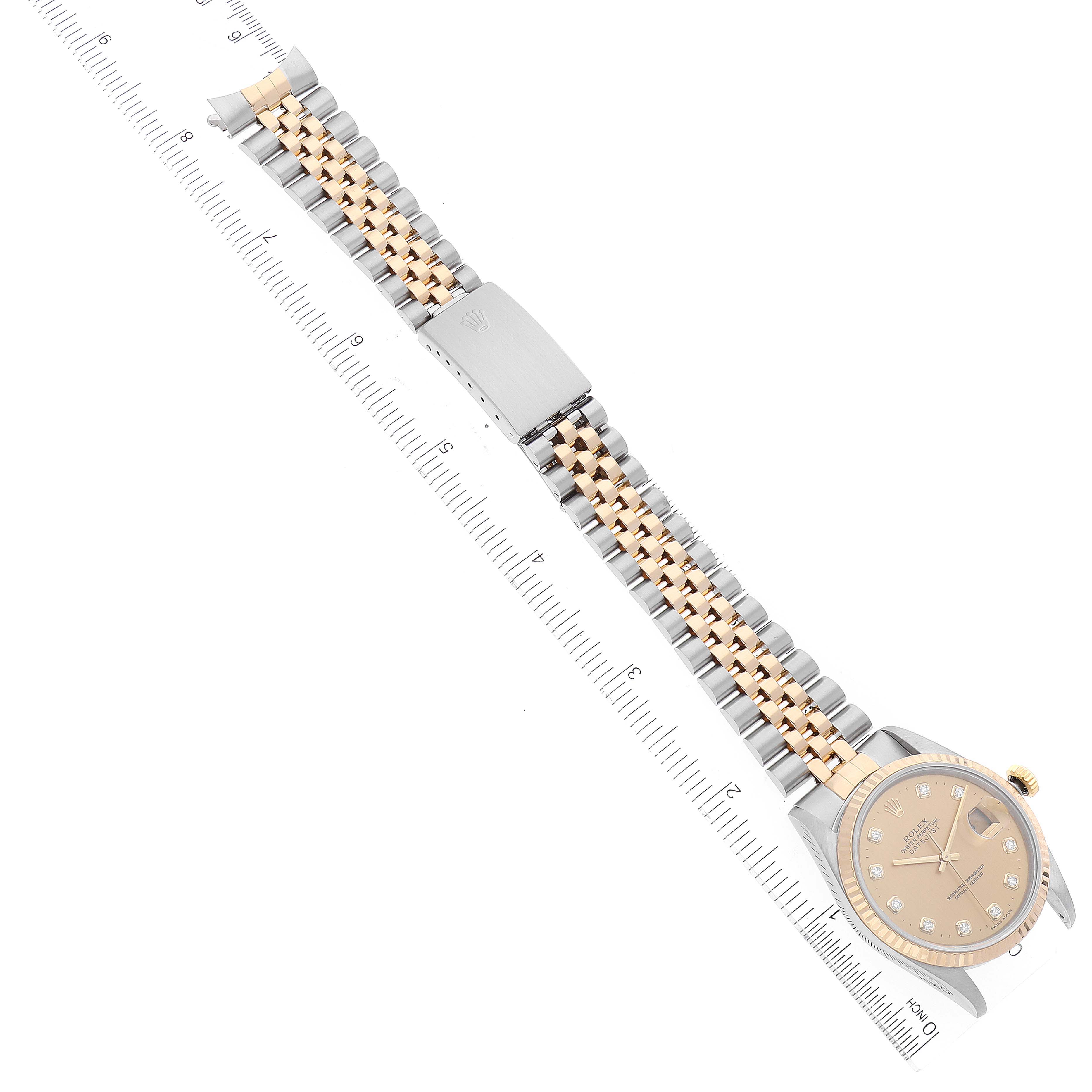 This image shows a Rolex Datejust 16233 Men's Steel and Gold (two tone) Champagne Dial 16233 Men's Steel and Gold (two tone) Champagne Dial watch lying flat, displaying the face, bracelet, and clasp alongside a ruler for scale.