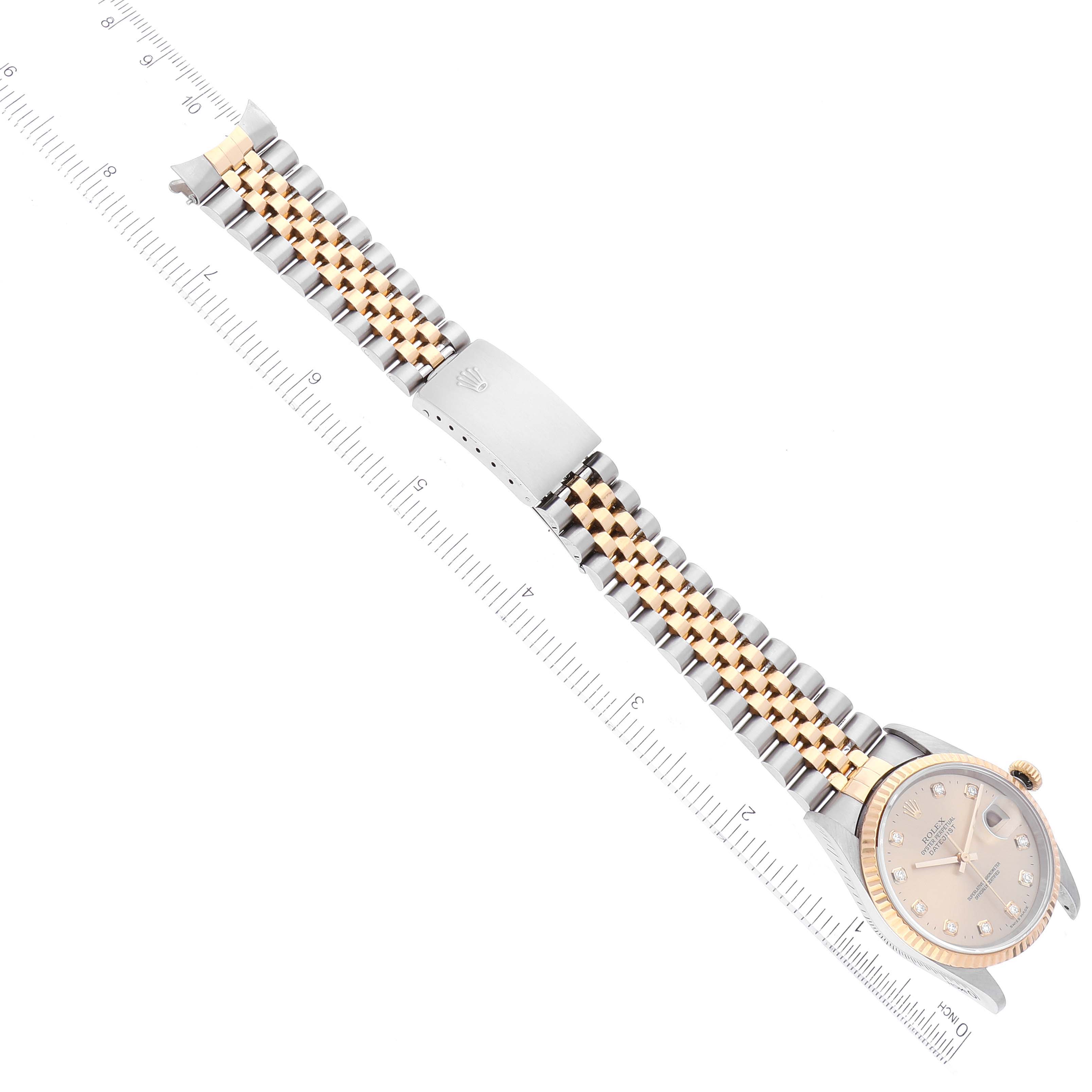 The image shows a top view of the Rolex Datejust 16233 Men's Steel and Gold (two tone) Champagne Dial 16233 Men's Steel and Gold (two tone) Champagne Dial watch, highlighting the face, bracelet, and clasp next to a ruler.