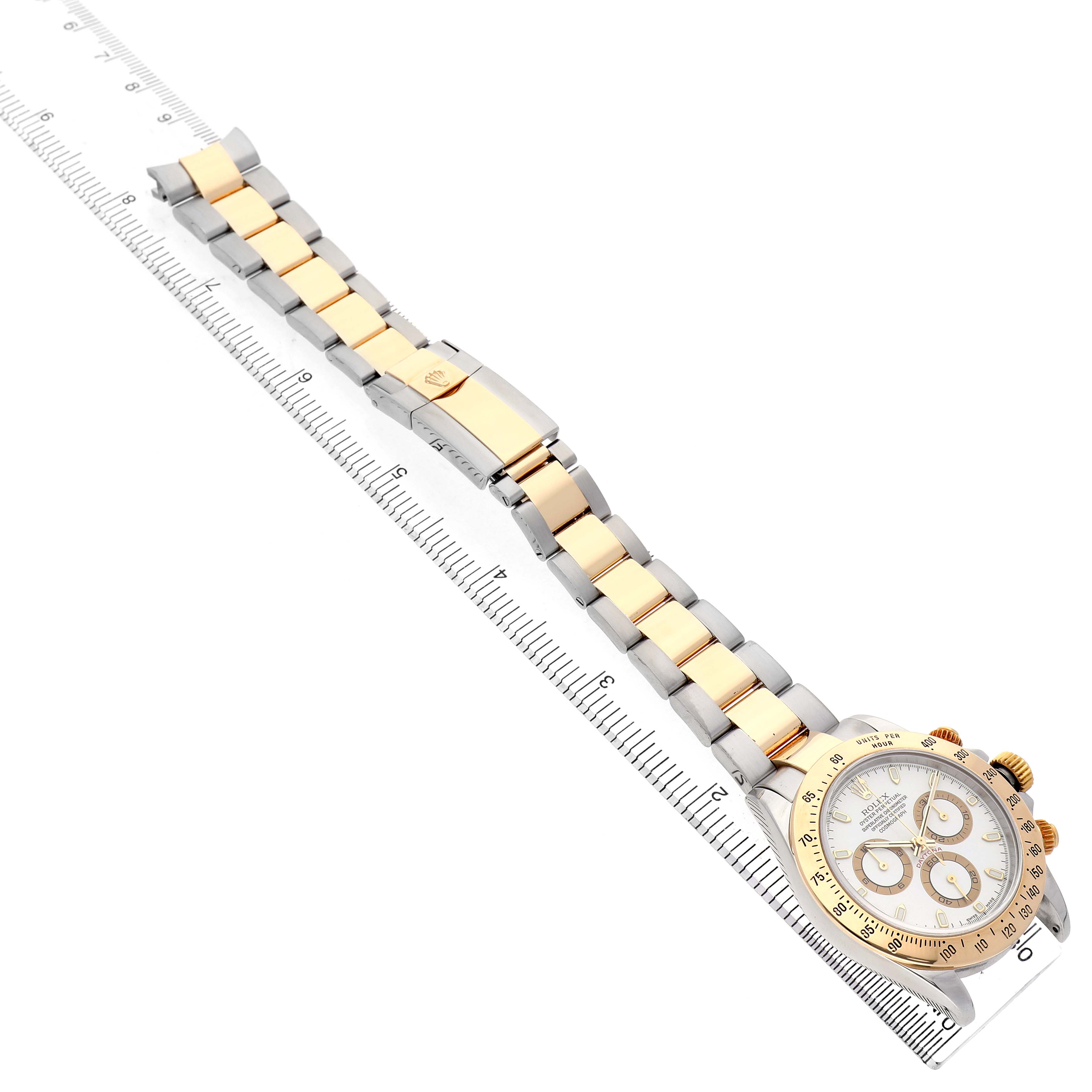 The Rolex Daytona 116523 Men's Stainless Steel White Dial watch is shown diagonally from the side, displaying its face and two-tone bracelet alongside a ruler.