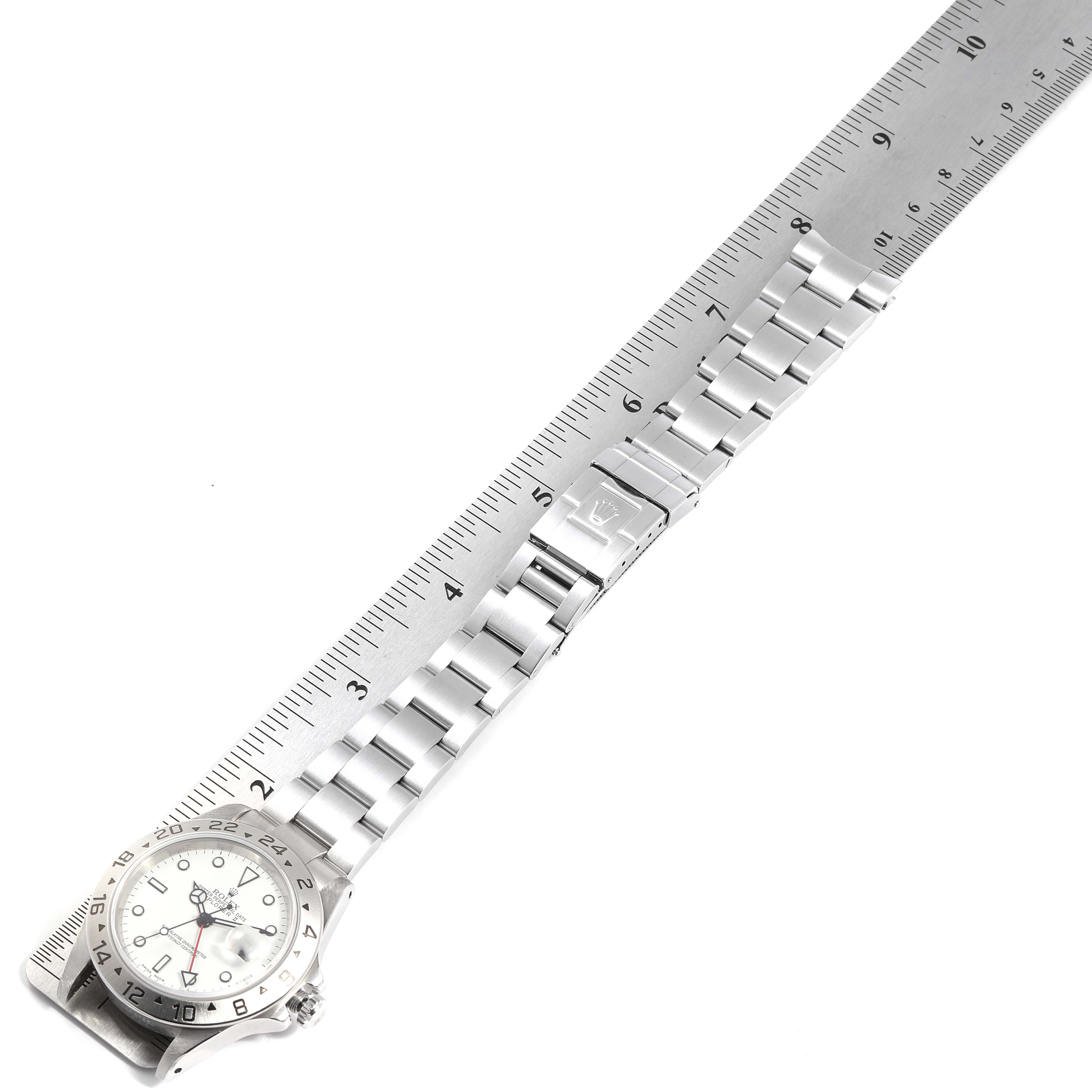 The image shows the Rolex Explorer 16570 Men
s Stainless Steel White Dial 16570 Men
s Stainless Steel White Dial watch laid flat alongside a ruler, highlighting its stainless steel bracelet and clasp.
