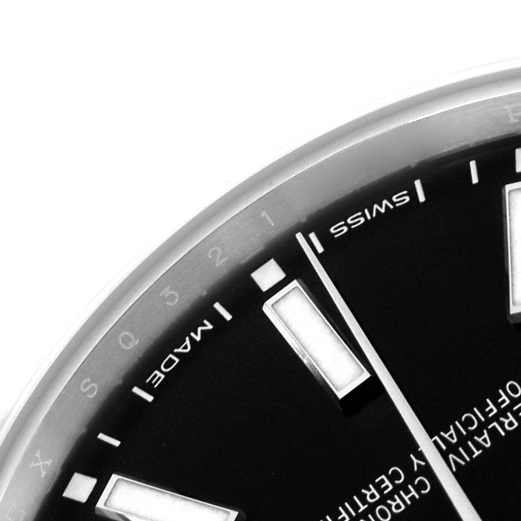The image shows a partial close-up of the Rolex Oyster Perpetual 114300 Men
s Stainless Steel Black Dial 114300 Men
s Stainless Steel Black Dial watch, focusing on the dial and markers.