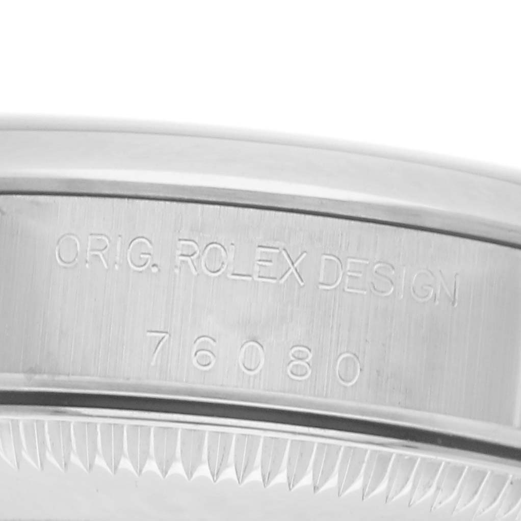 The image shows the side view of a Rolex Oyster Perpetual 76080 Women
s Stainless Steel Pink Dial 76080 Women
s Stainless Steel Pink Dial case with engraved "O.R.I.G. ROLEX DESIGN" and model number "76080".