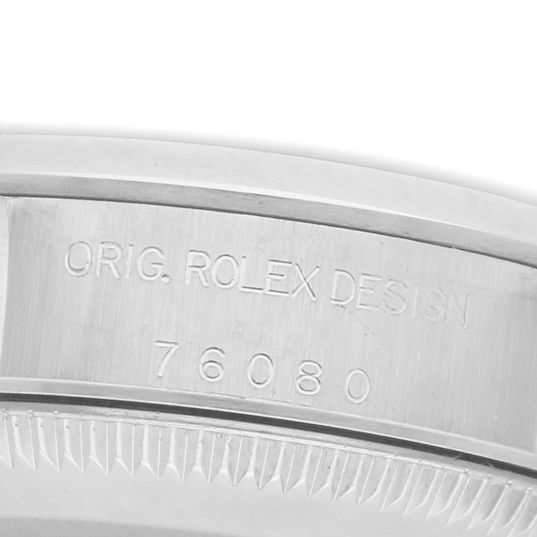 The image shows a close-up of the side of a Rolex Oyster Perpetual 76080 Women
s Stainless Steel Pink Dial 76080 Women
s Stainless Steel Pink Dial watch, focusing on the engraved "ORIG. ROLEX DESIGN 76080."