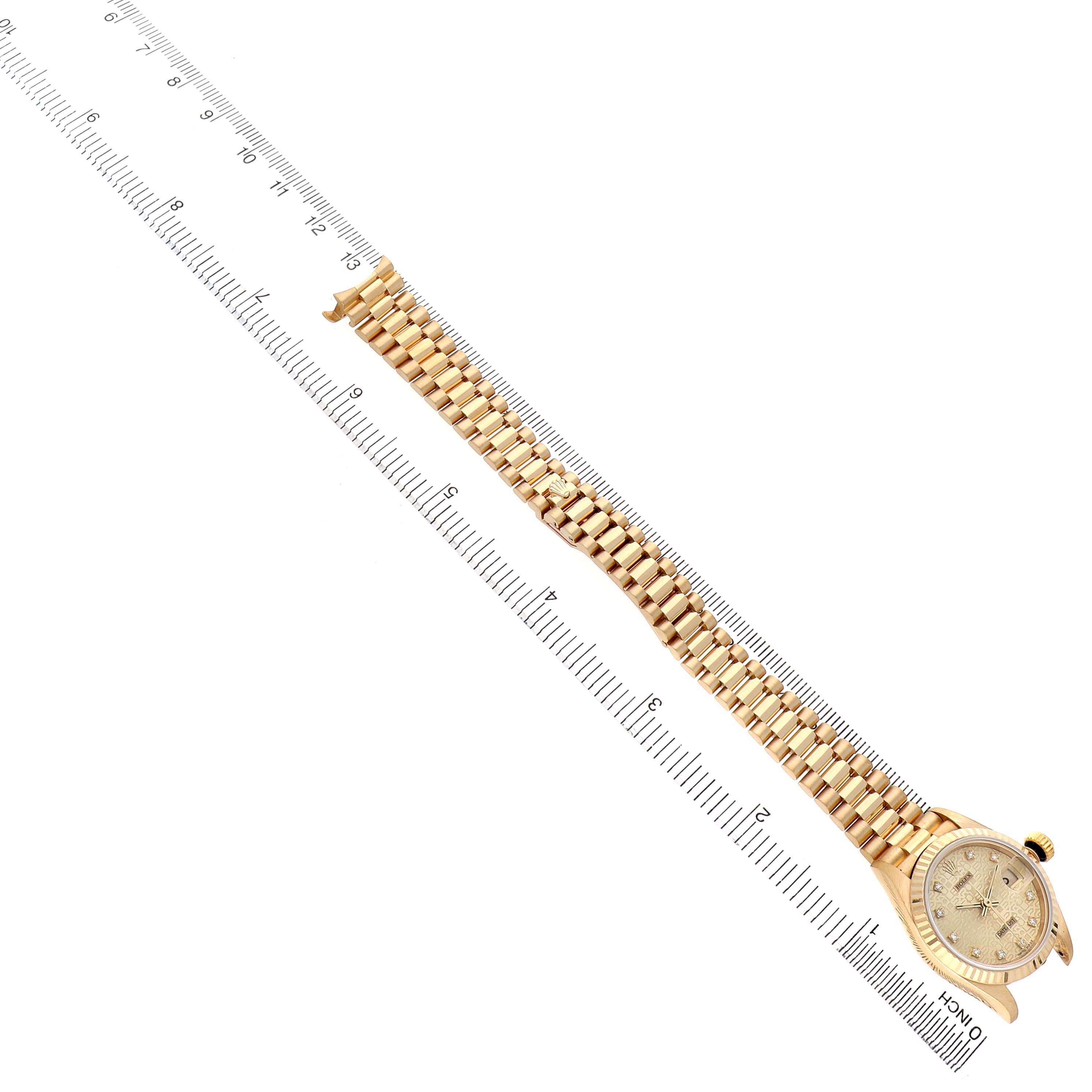 The Rolex President 69178 Women's Yellow Gold Champagne Dial watch is shown at a diagonal angle, displaying the face, bezel, and full bracelet alongside a ruler for scale.