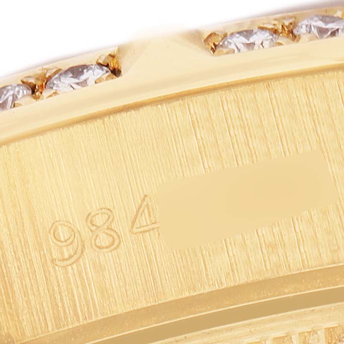 This close-up image shows the engraved serial number and diamond-studded bezel of a Rolex President 69258 Women's Yellow Gold White Dial watch.