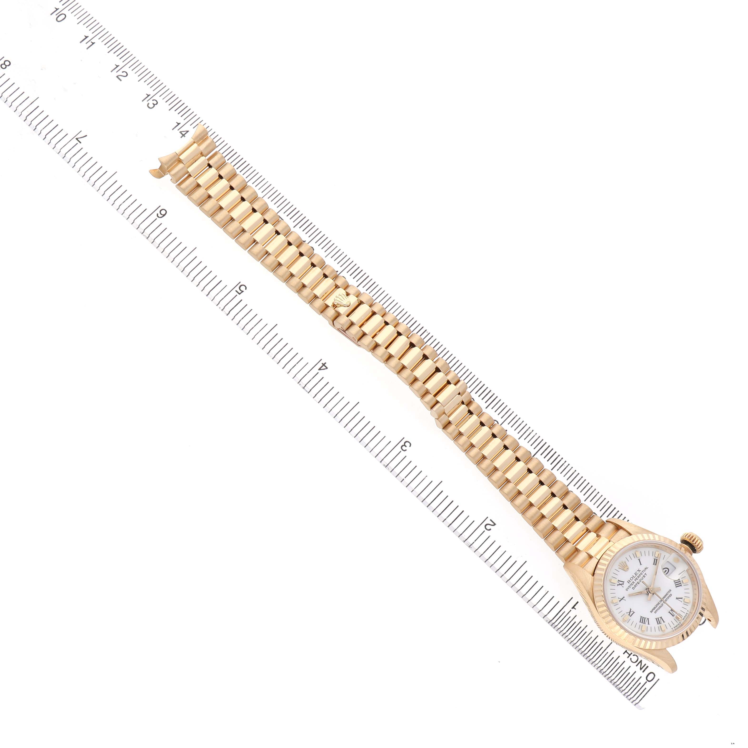 The Rolex President 69178 Women's Yellow Gold White Dial watch is shown from the top angle, displaying the watch face, bracelet, and clasp against a ruler.