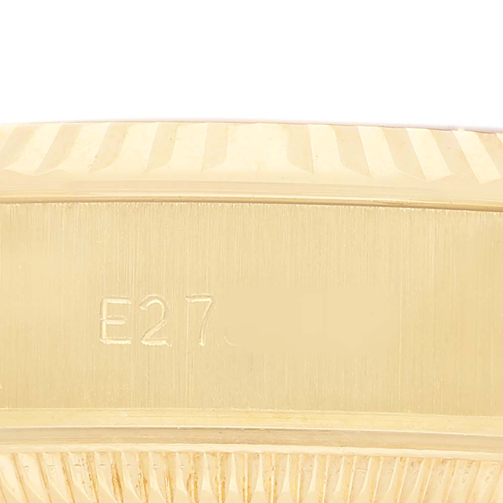 The image shows a textured close-up of the bezel and part of the case back of the Rolex President 69178 Women's Yellow Gold White Dial watch.