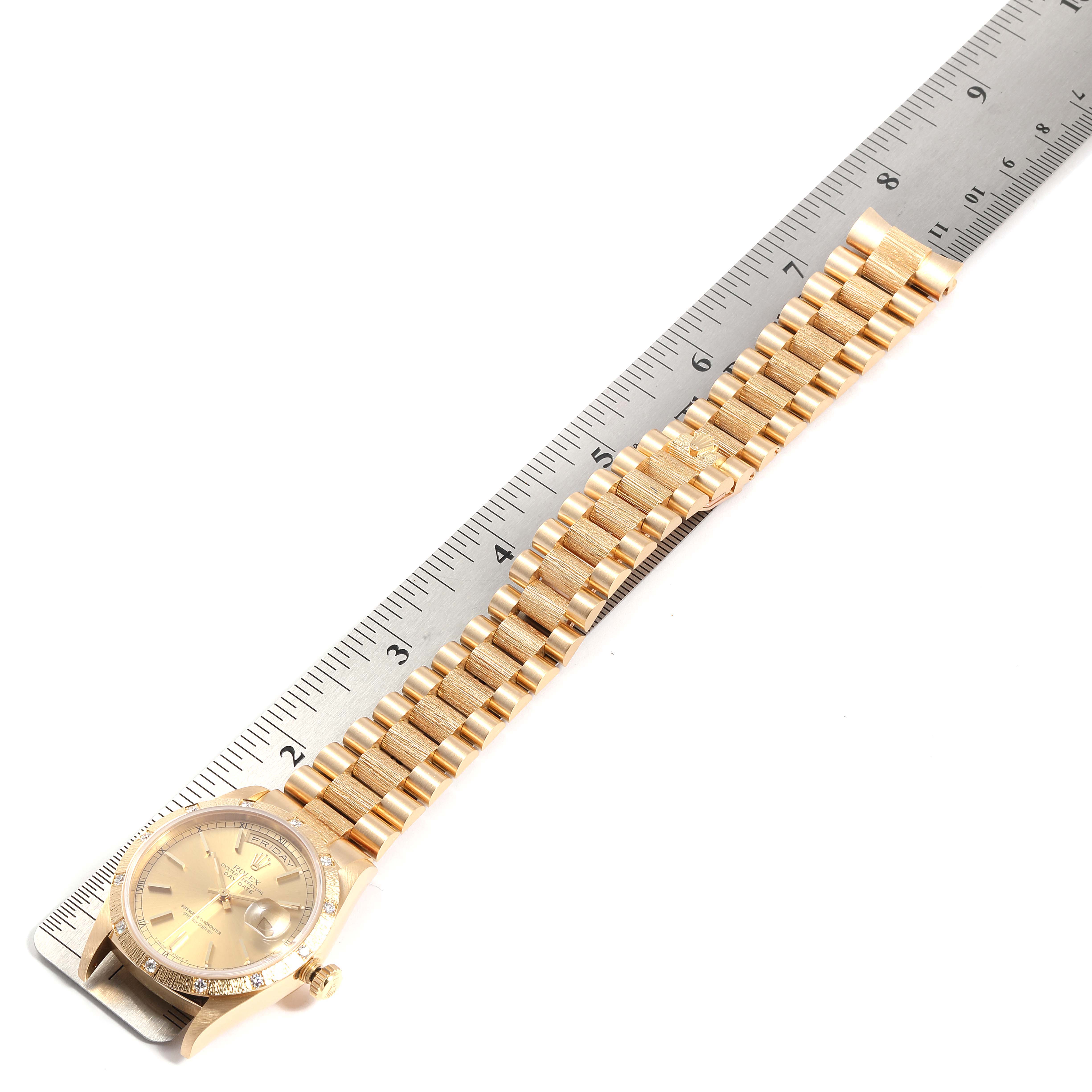 The Rolex President 18308 Men
s Yellow Gold Champagne Dial 18308 Men
s Yellow Gold Champagne Dial model watch is shown laying flat with its gold bracelet extended next to a ruler.