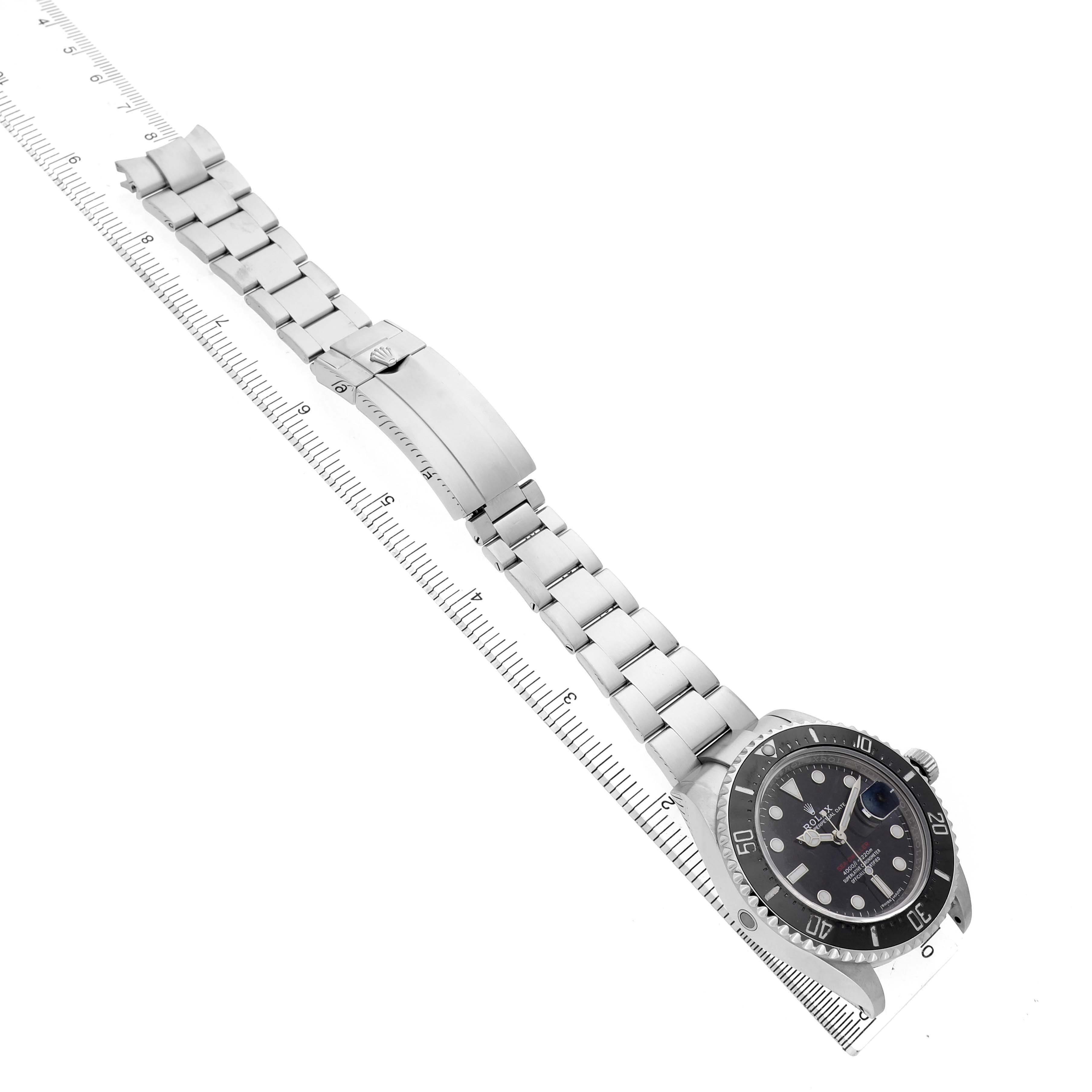The Rolex Sea-Dweller 126600 Men's Stainless Steel Black Dial is shown at an angle displaying the bracelet fully extended alongside a ruler, highlighting its length.