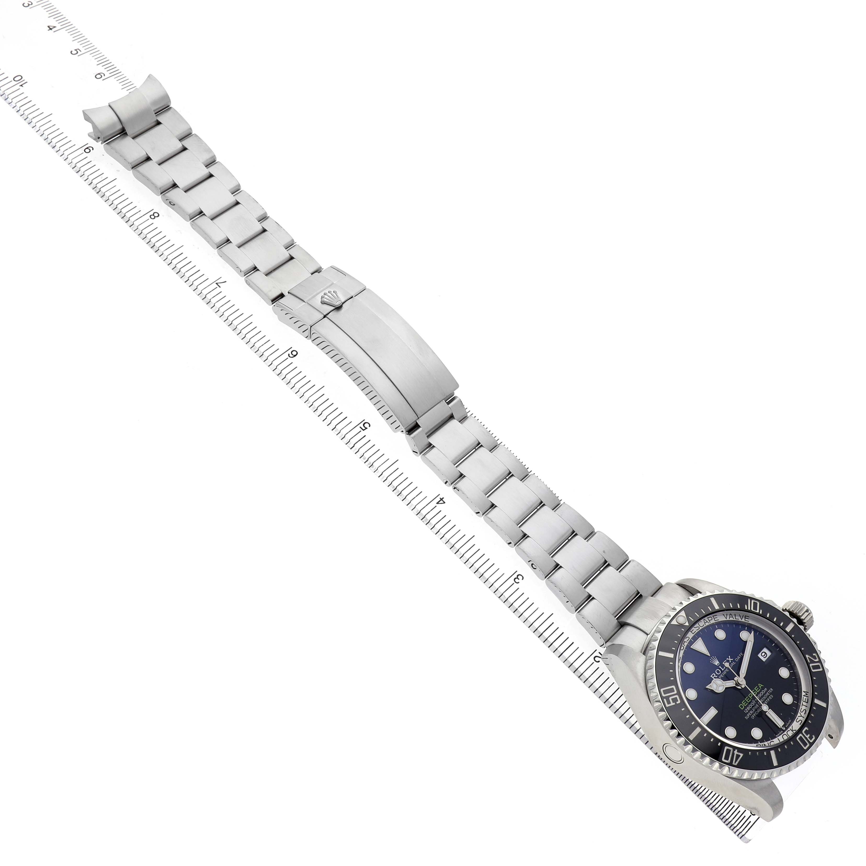 The Rolex Sea-Dweller 126660 Men's Stainless Steel Blue Dial watch is displayed diagonally, highlighting the bracelet, clasp, and face, with a ruler for scale.