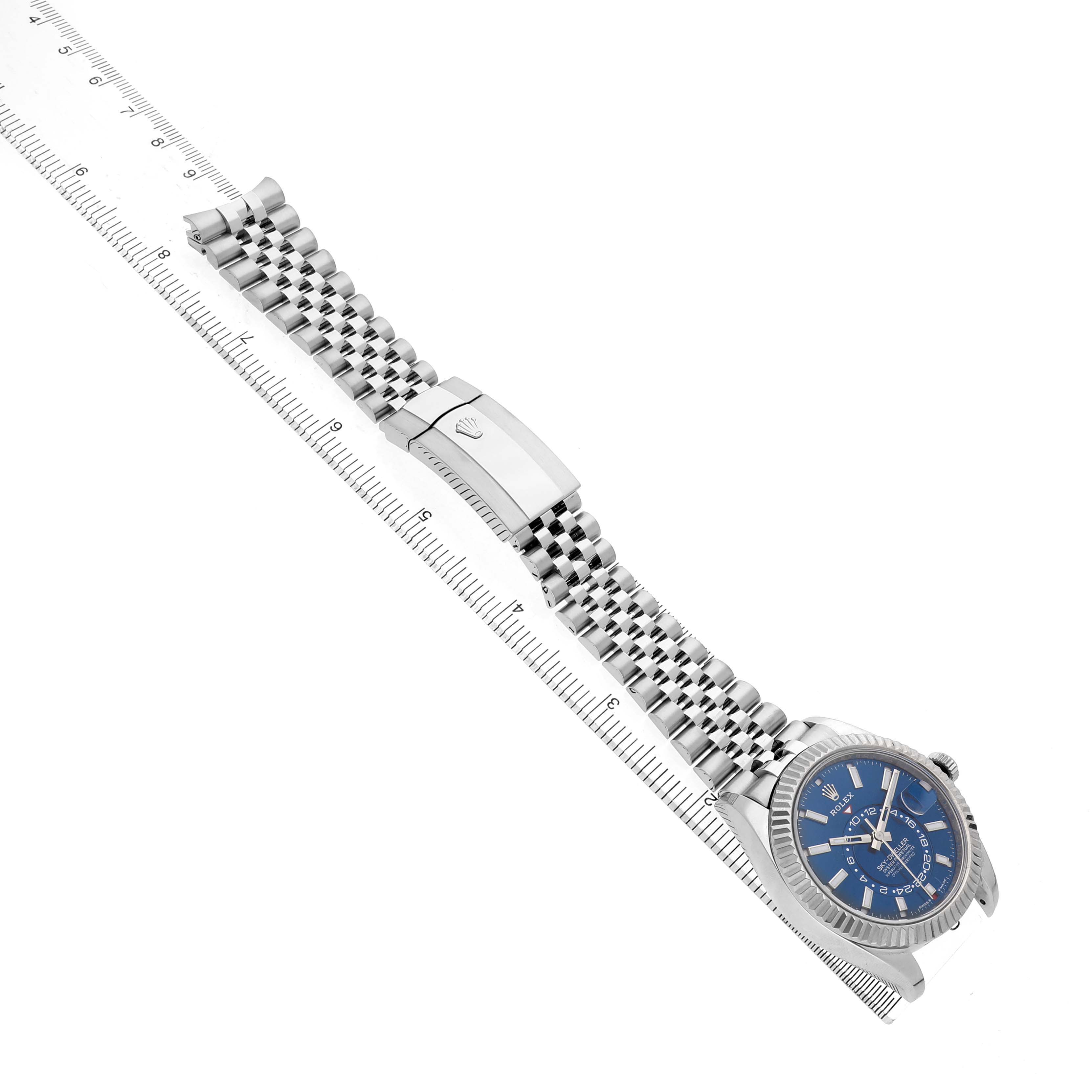 The Rolex Sky-Dweller 336934 Men's Stainless Steel Blue Dial watch is shown at an angled top view, highlighting the dial, bracelet, and clasp alongside a ruler.