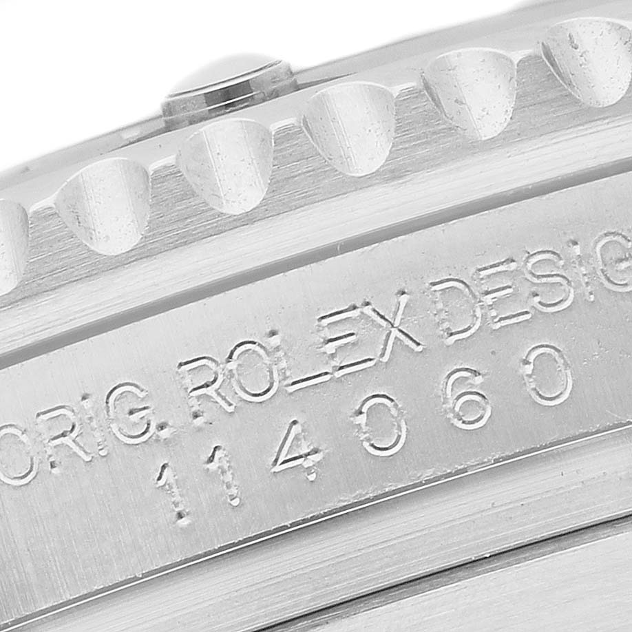 The image shows a close-up of the Rolex Submariner 114060 Men's Stainless Steel Black Dial's bezel edge and engraved model information.