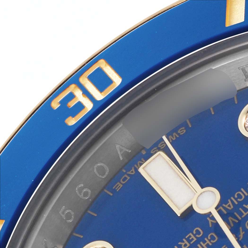 The image shows a close-up of the Rolex Submariner 116613 Men's Steel and Gold (two tone) Blue Dial 116613 Men's Steel and Gold (two tone) Blue Dial's blue dial, bezel, and part of the minute hand at a slight angle.