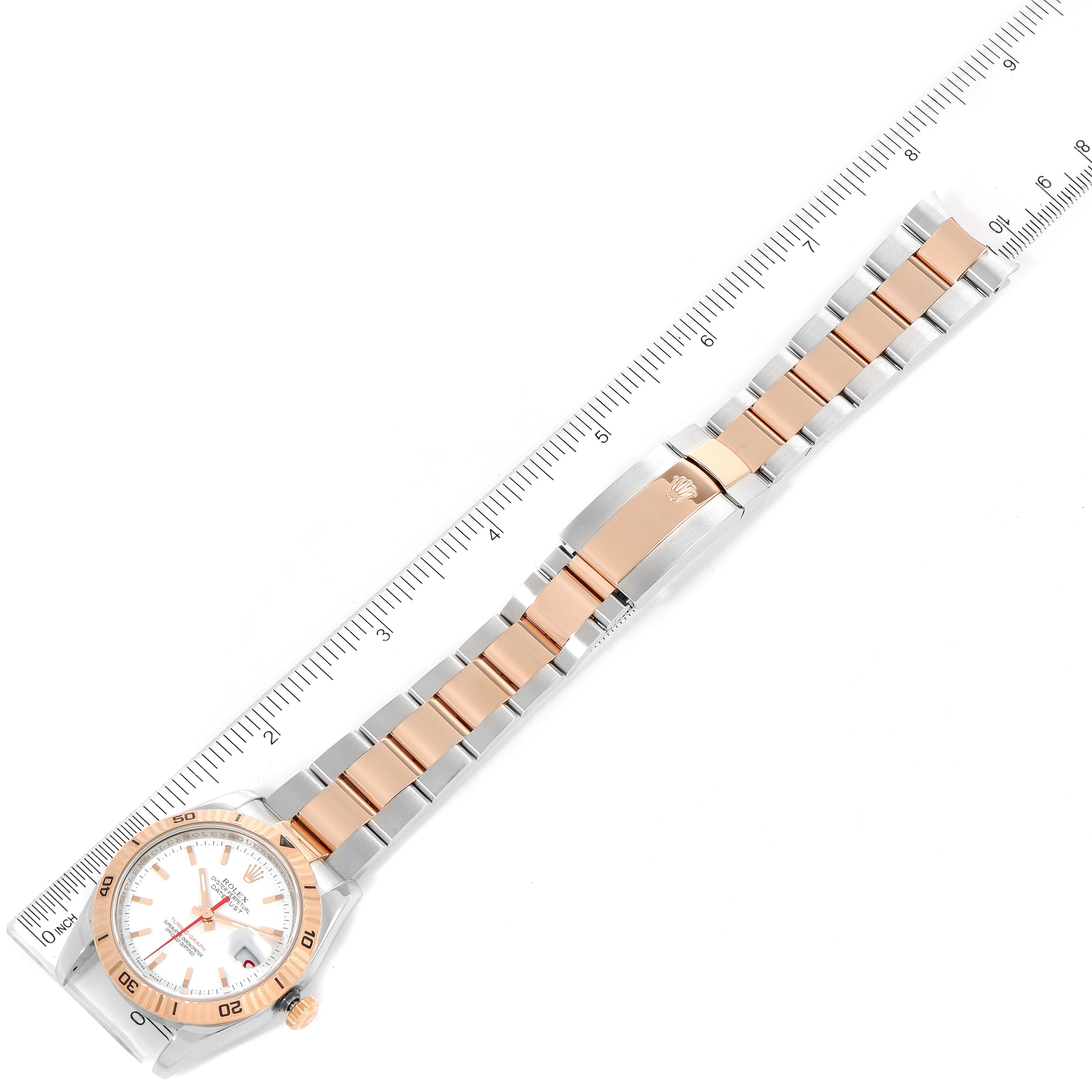 The Rolex Turn-o-Graph 116261 Men
s Steel and Gold (two tone) White Dial 116261 Men
s Steel and Gold (two tone) White Dial watch is displayed from a top-down angle, showing the entire watch and bracelet alongside a ruler.