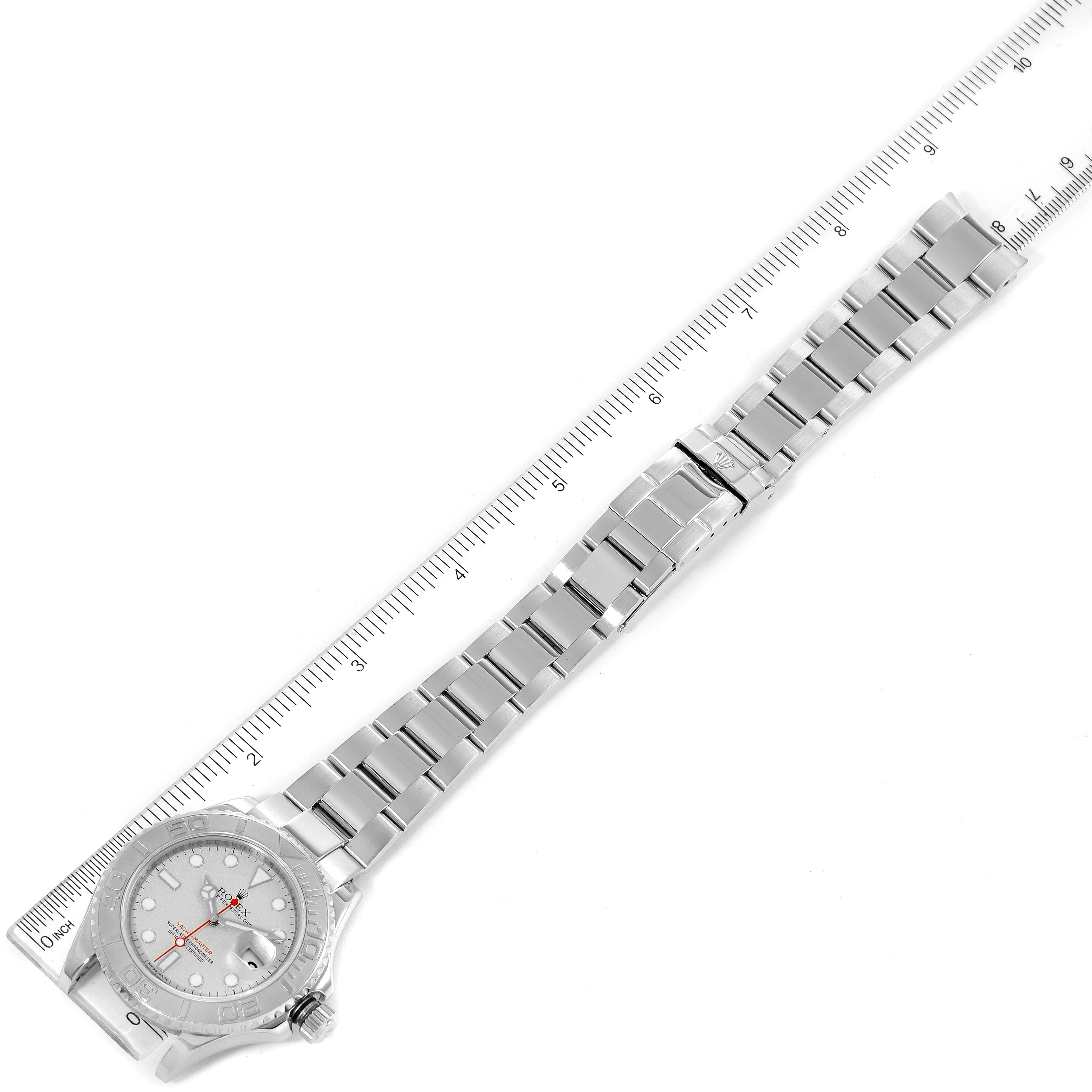 The image shows an aerial view of a Rolex Yacht-Master 16622 Men
s Stainless Steel Silver Dial 16622 Men
s Stainless Steel Silver Dial watch, displaying its face, bracelet, and clasp alongside a ruler for scale.