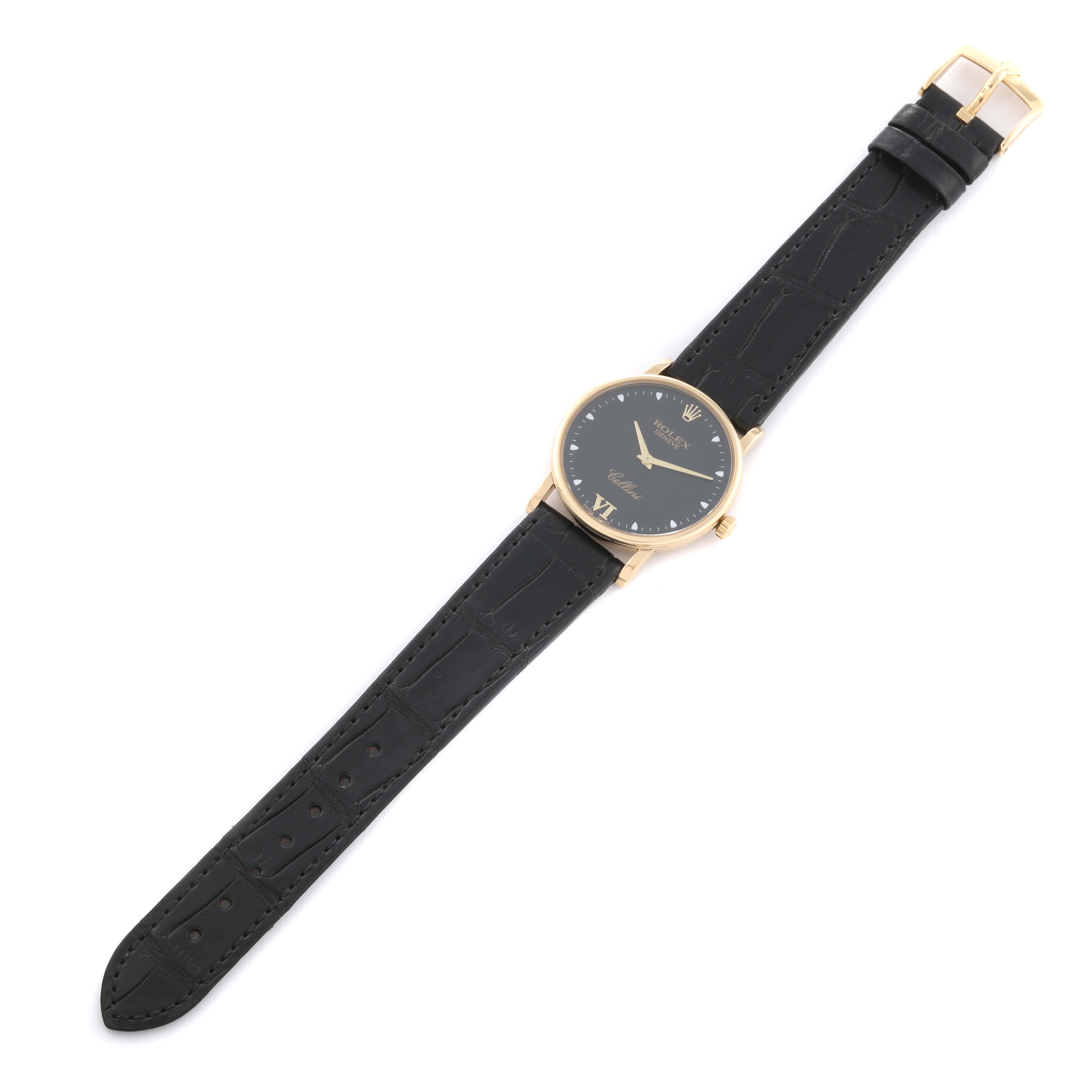 The image shows a Rolex Cellini 5115 Men's Yellow Gold Black Dial 5115 Men's Yellow Gold Black Dial watch in a top-down angle, highlighting its black leather strap and round gold case with a black dial.