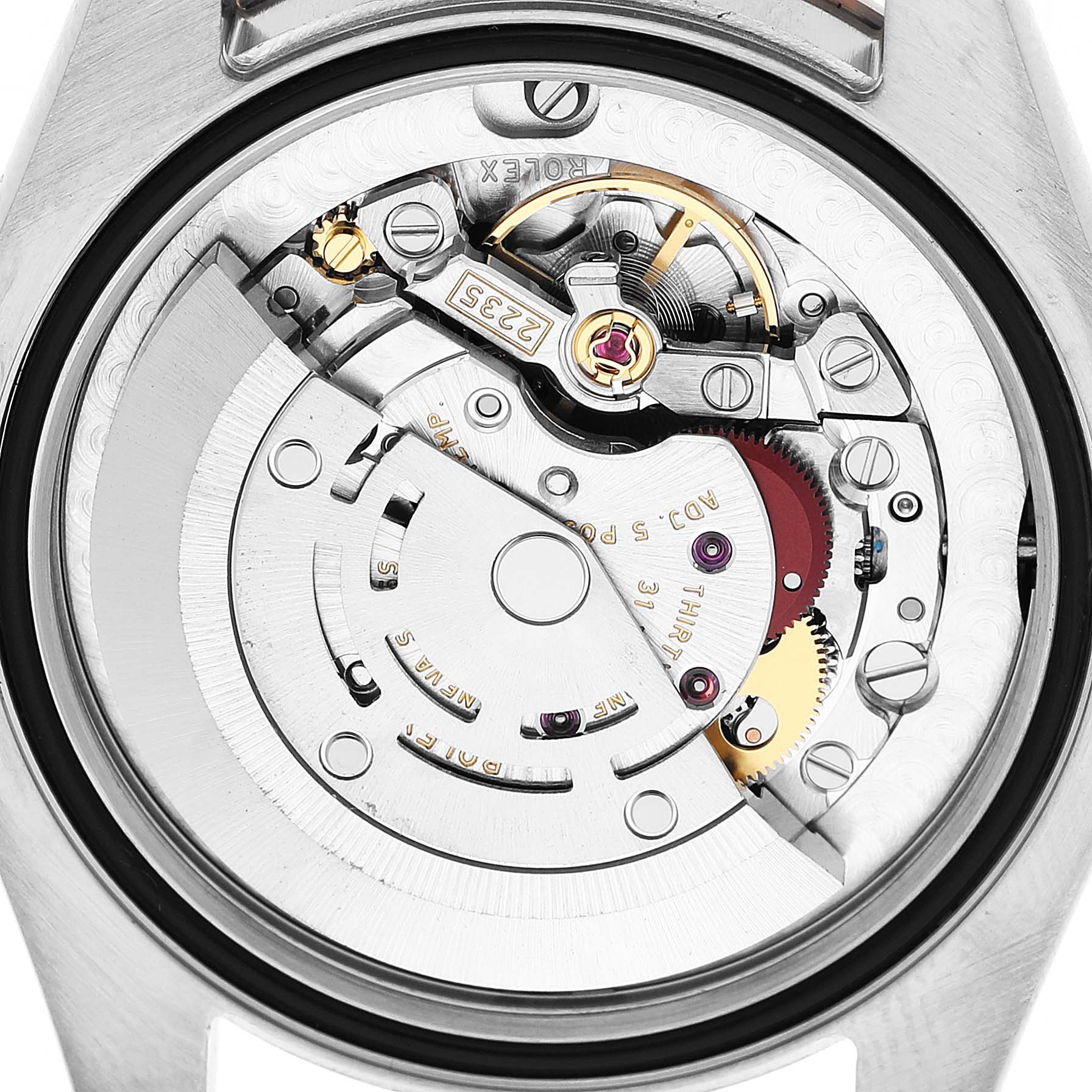 The image shows the movement mechanism of the Mid-Size Rolex watch from a rear angle, highlighting gears and components.