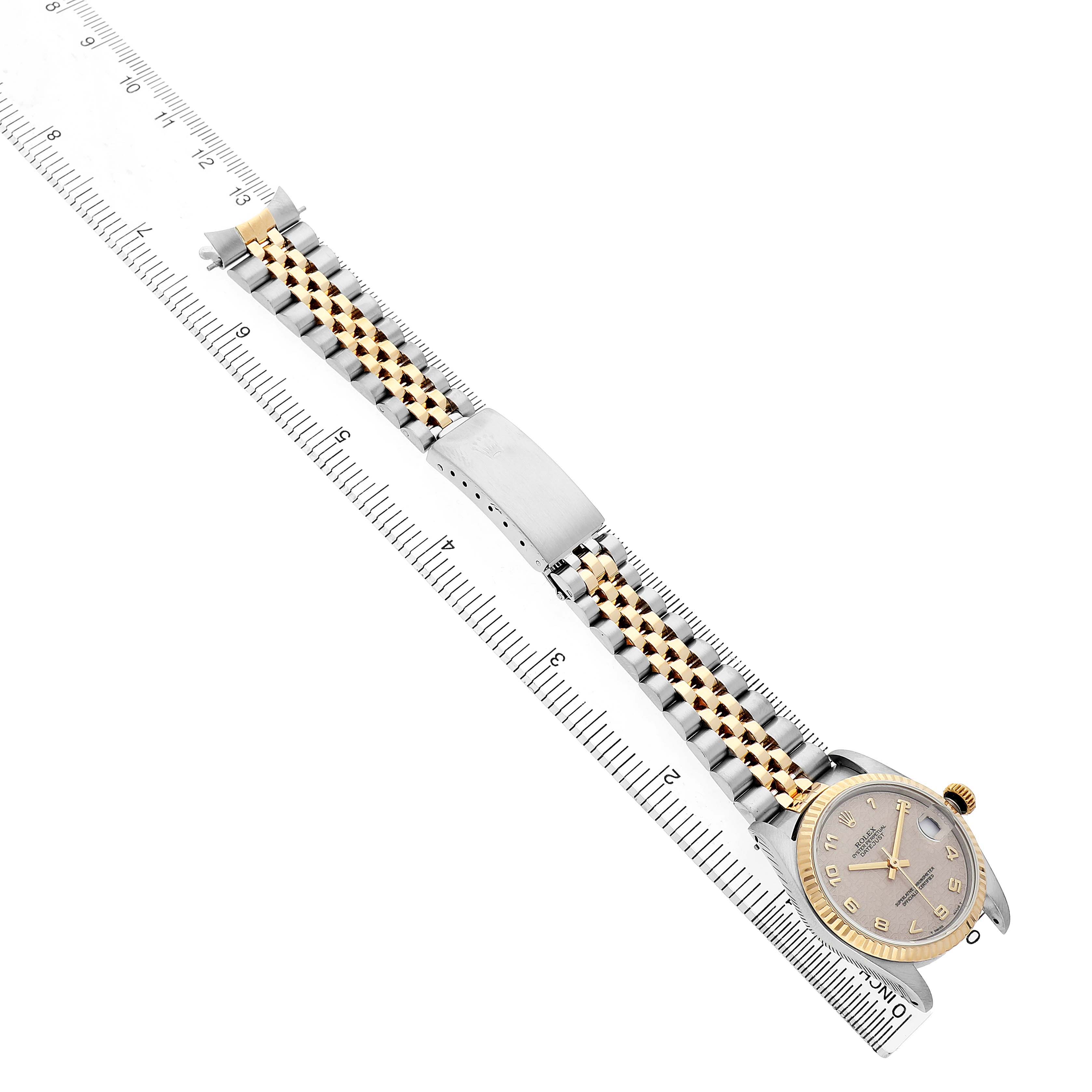The Rolex Mid-Size 68273 Women's Steel and Gold (two tone) White Dial watch is shown at an overhead angle, displaying its face, bracelet, and clasp alongside a ruler for scale.