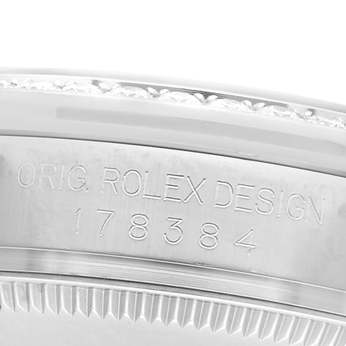 The image shows a close-up of the side of a Rolex Mid-Size 178384 Women
s Stainless Steel Purple Dial 178384 Women
s Stainless Steel Purple Dial watch, focusing on its engraved design numbers.