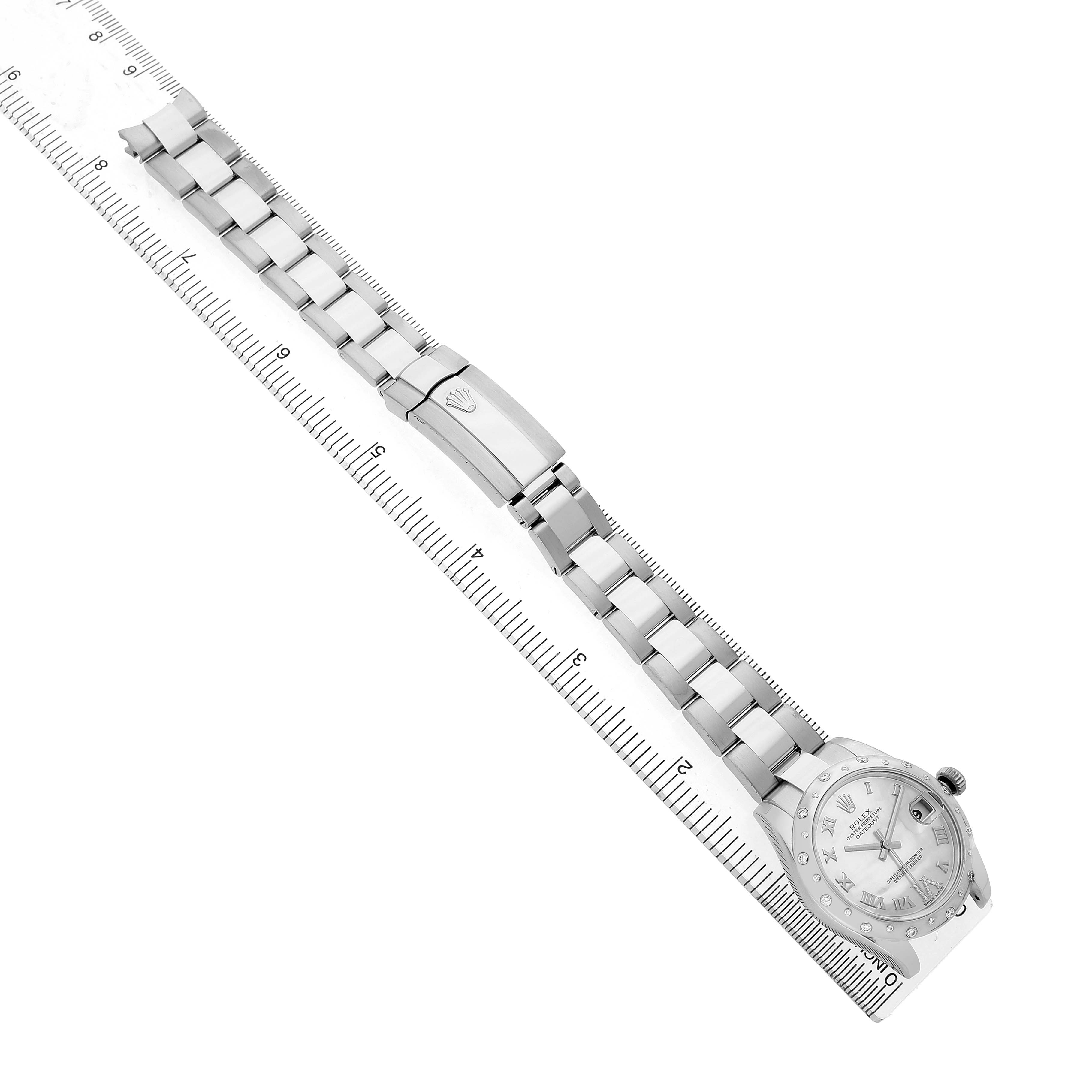The Rolex Mid-Size 178344 Women's Stainless Steel Mother of Pearl Dial watch is shown from above, displaying the face, metal bracelet, and clasp alongside a ruler.