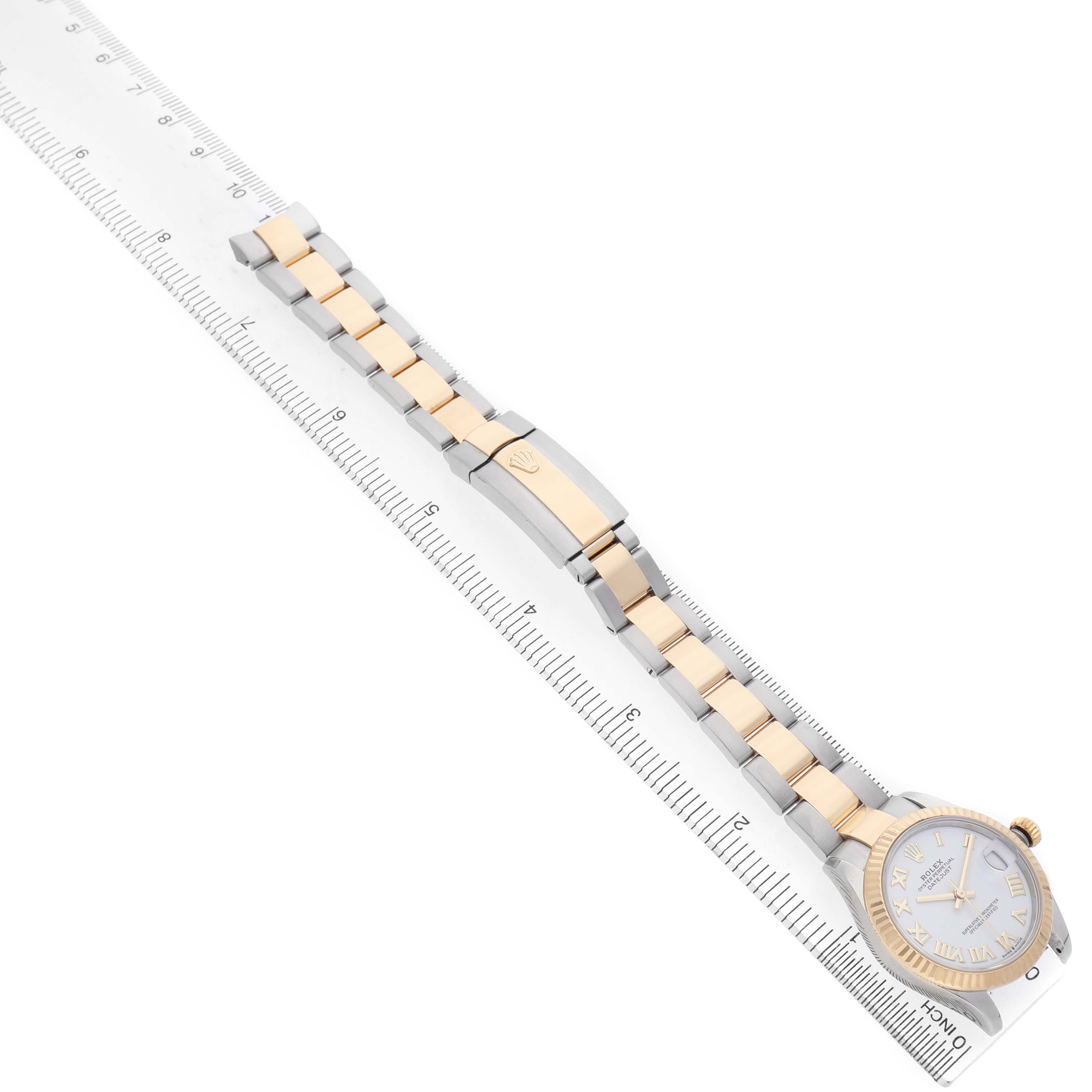 The Rolex Mid-Size 278273 Women's Steel and Gold (two tone) White Dial watch is shown from an overhead angle, highlighting the face, bracelet, and clasp on a measuring ruler.
